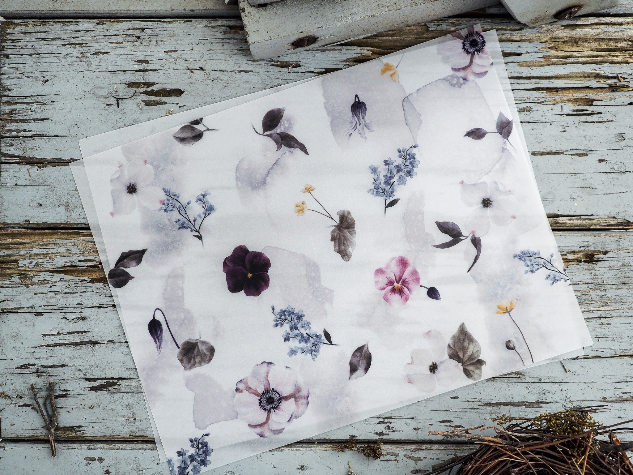 Watercolor floral sticker sheet patterned with soft pastel pansies, deep purple blossoms, and delicate blue spring sprigs.