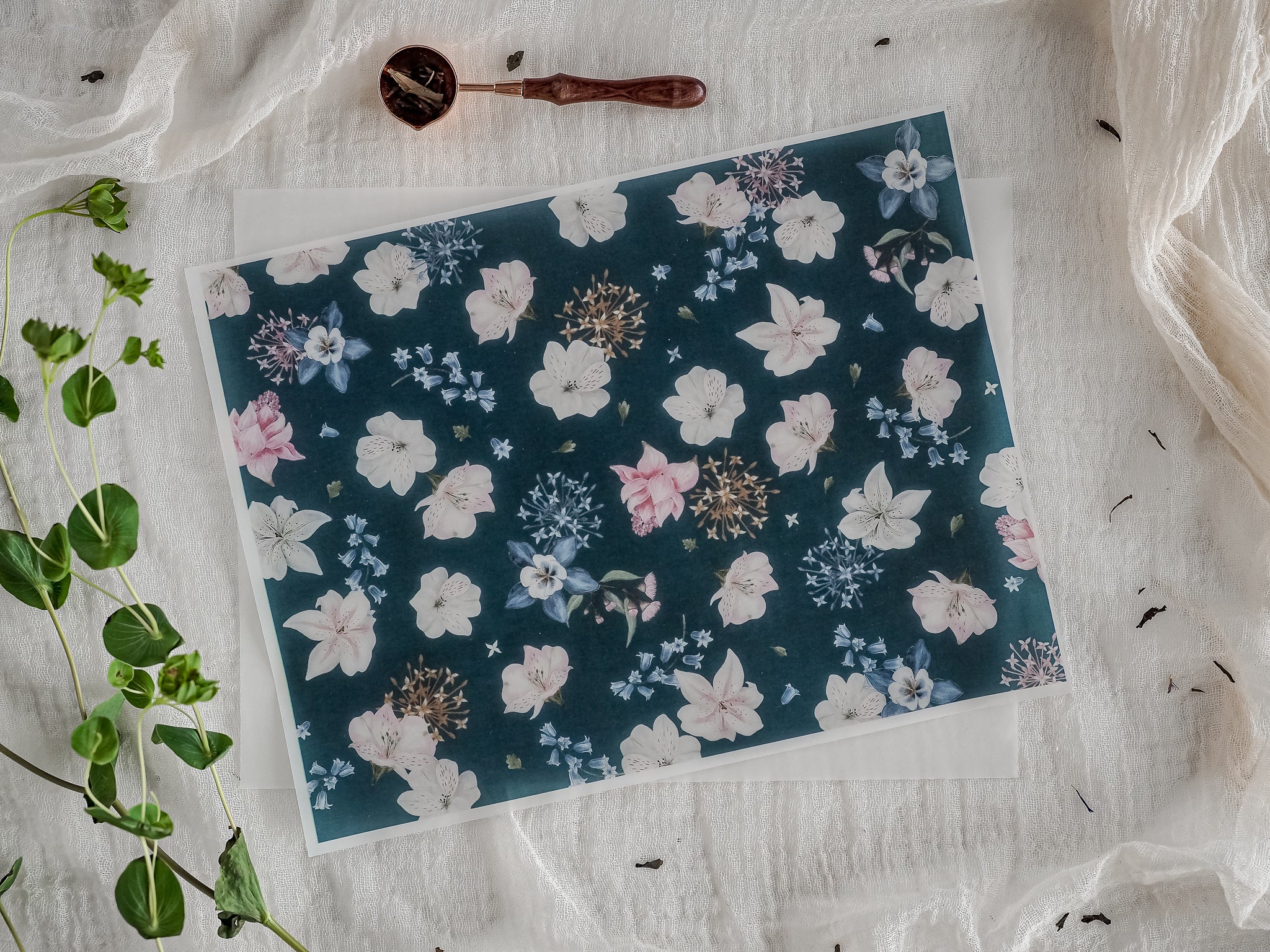 Elegant botanical pattern on a dark teal background featuring clustered lilies in cream, blush pink, and soft blue tones.