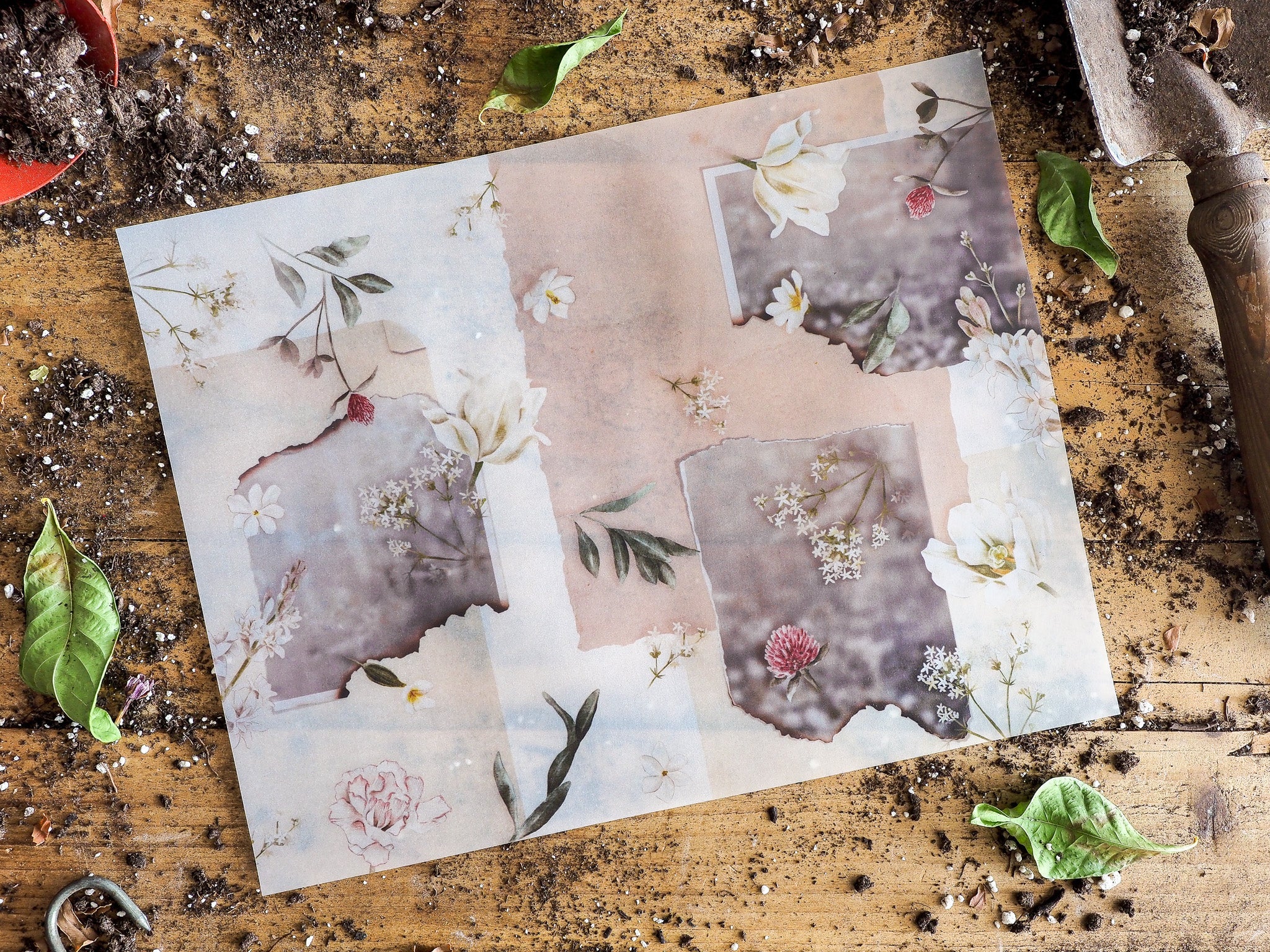 Delicate scrapbooking paper with a faded botanical design, featuring soft watercolor blooms, muted blush tones, and delicate green foliage.
