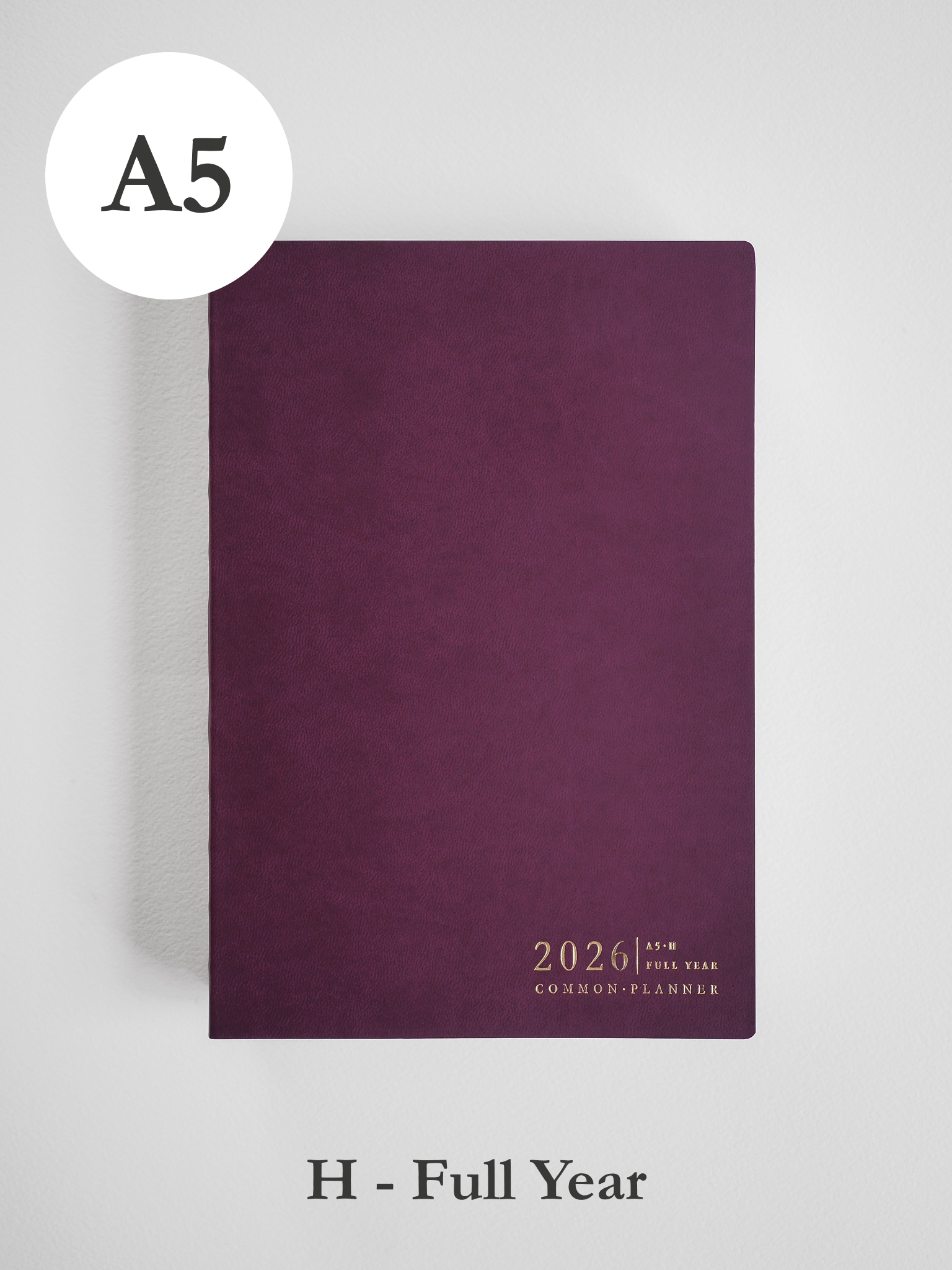 Rich, deep burgundy A5 planner cover for 2026, featuring subtle text branding that reads "Common Planner Full Year."