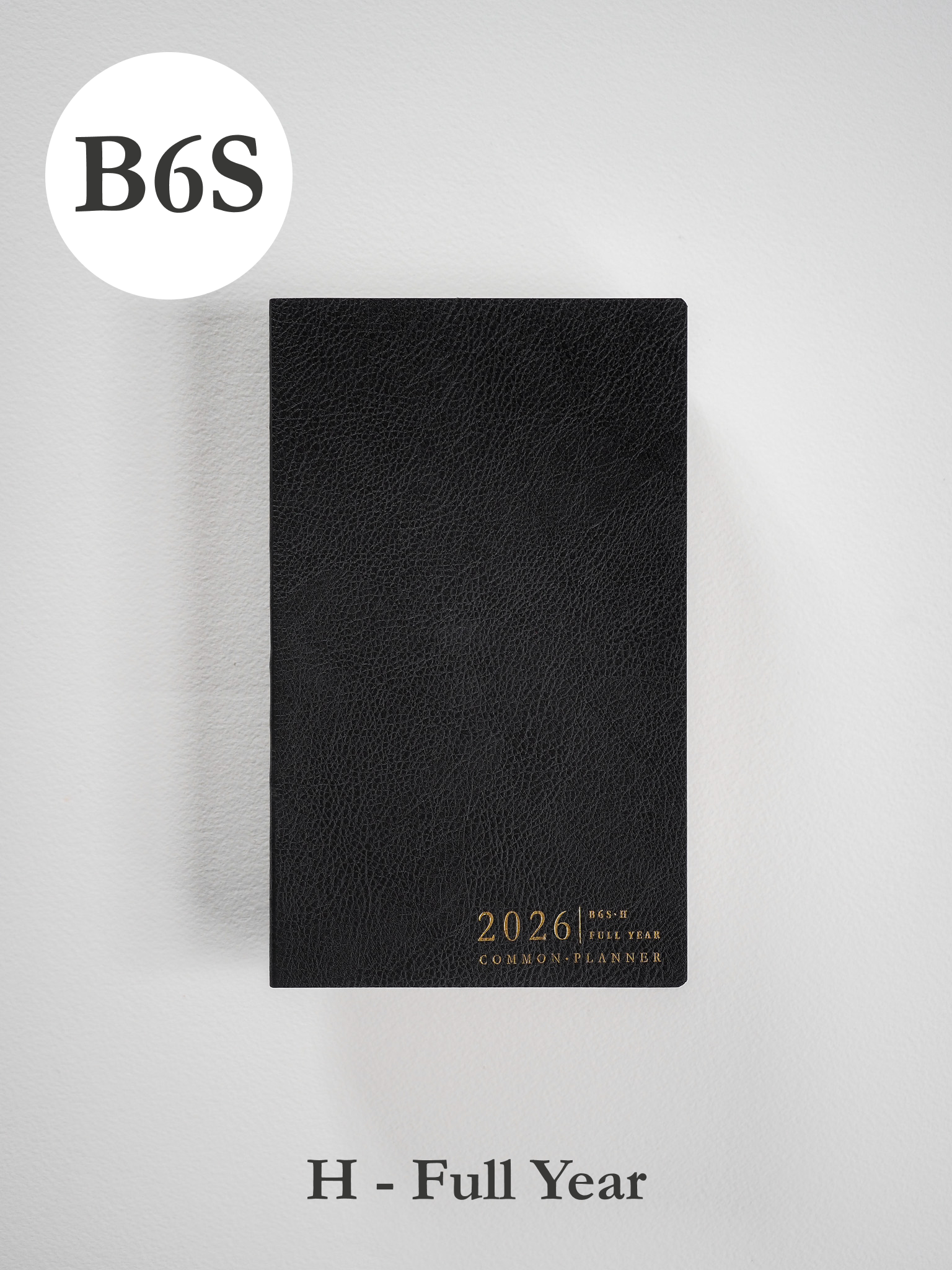 Sleek black B6 slim planner cover with a textured finish, featuring elegant gold foil lettering for the 2026 common planner.