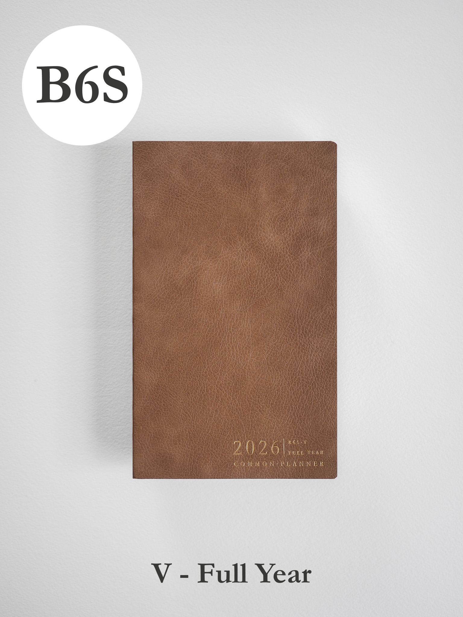 Minimalist B6 vertical planner in deep brown faux leather, subtly embossed with "2026" and the "Common Planner" title.