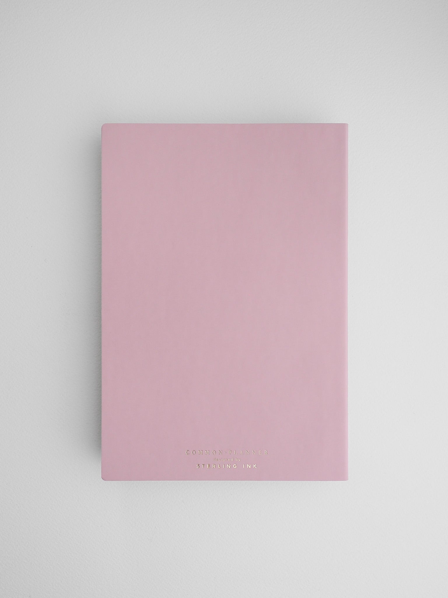 Elegant pastel pink planner notebook featuring subtle "Common Planner" branding, ideal for organizing a full year of undated journal entries.