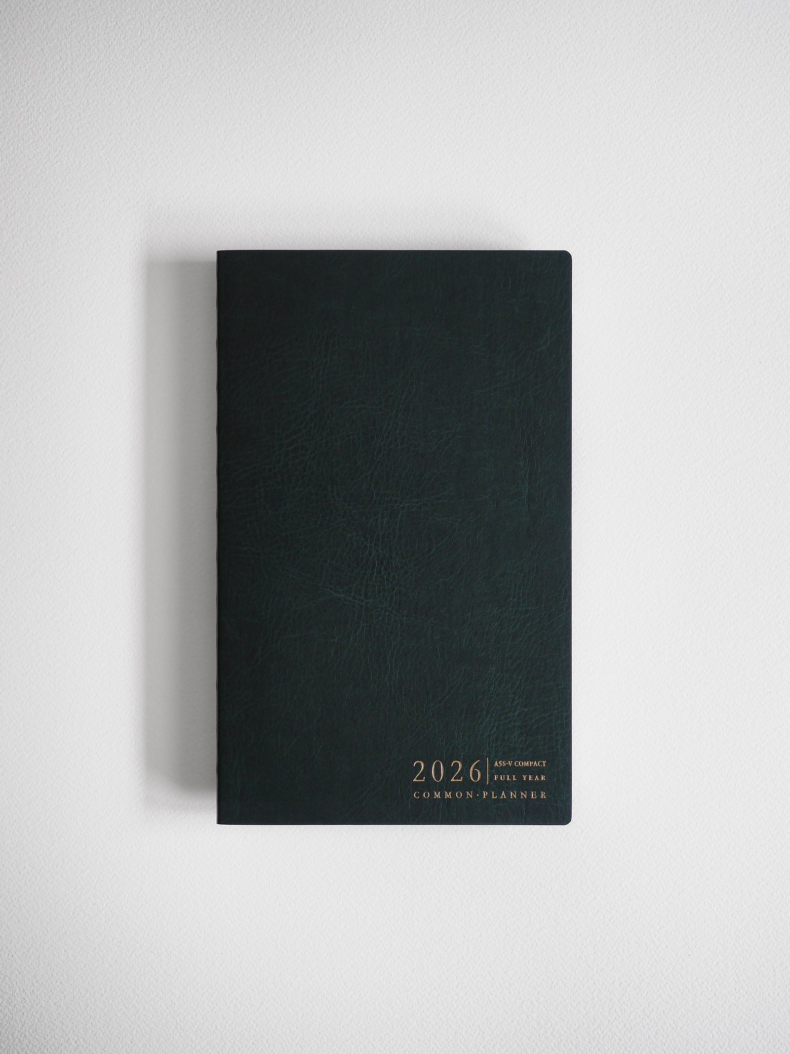 Sleek A5 vertical planner with a matte black cover, featuring minimal gold foil typography that reads "2026 Common Planner."