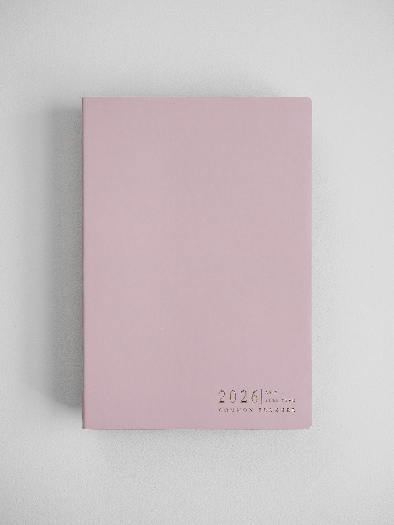 Elegant blush pink A5 planner featuring centered black typography that reads "2026 A5 Full Year Common Planner."