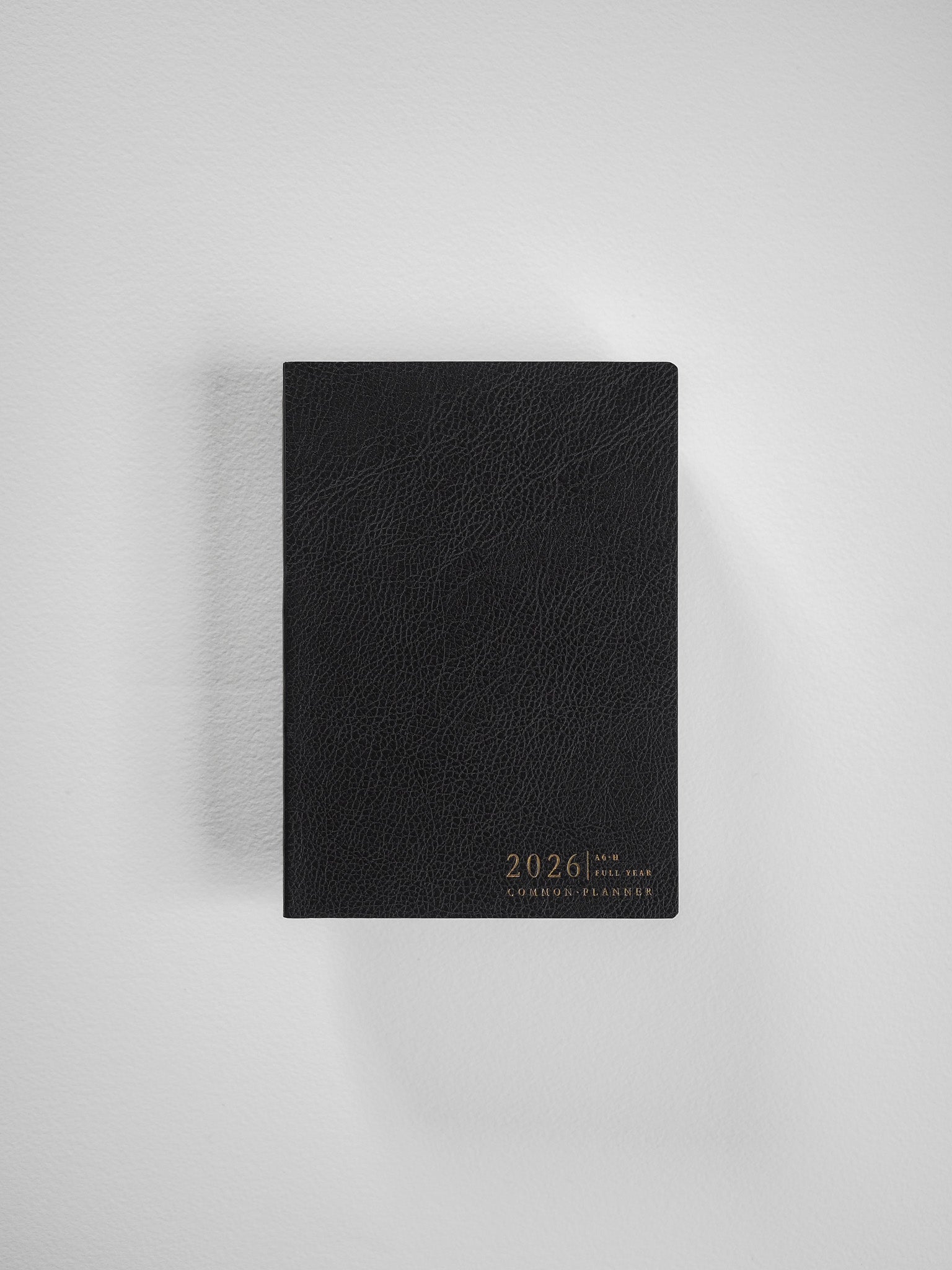 Sleek black A6 planner featuring a sophisticated, embossed faux leather texture and personalized with the minimalist "2026 Common Planner" title.