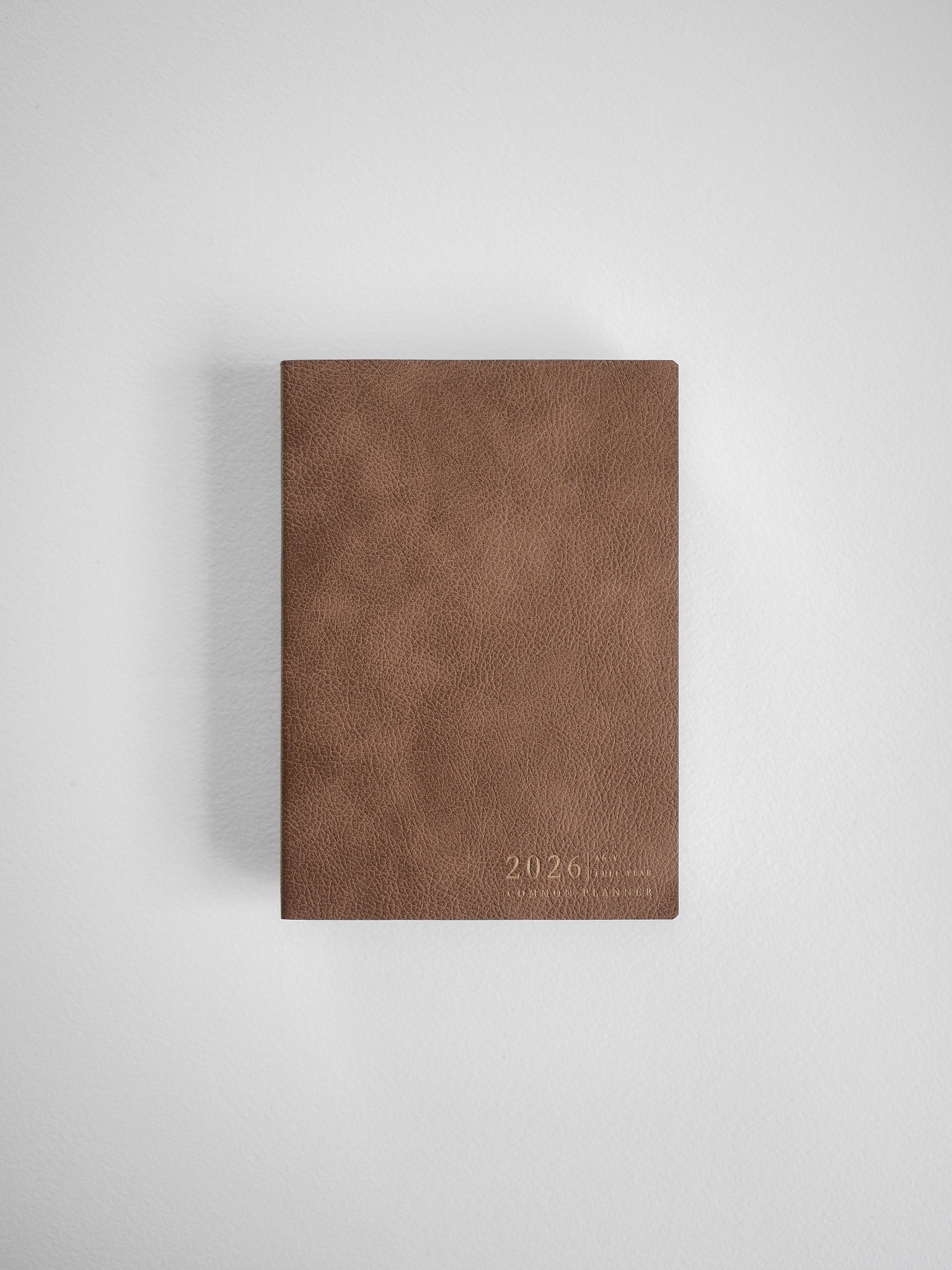 Solid A6 vertical planner cover in warm mocha brown faux leather, featuring a clean, minimalist design subtly embossed with the year 2026.