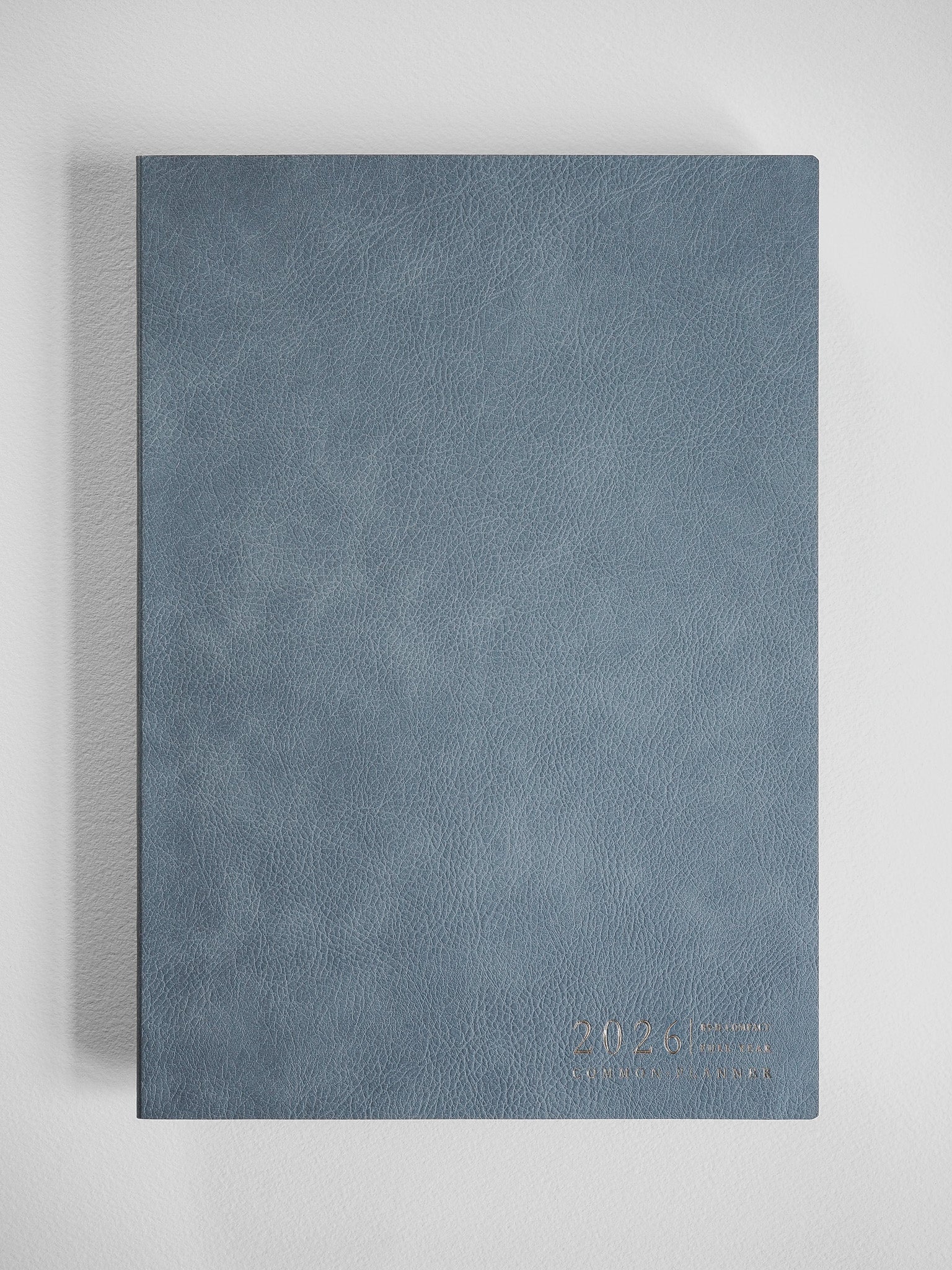 Elegant slate blue B5 planner with a subtle faux-leather texture, embossed with the year 2026, ready for writing and organization.