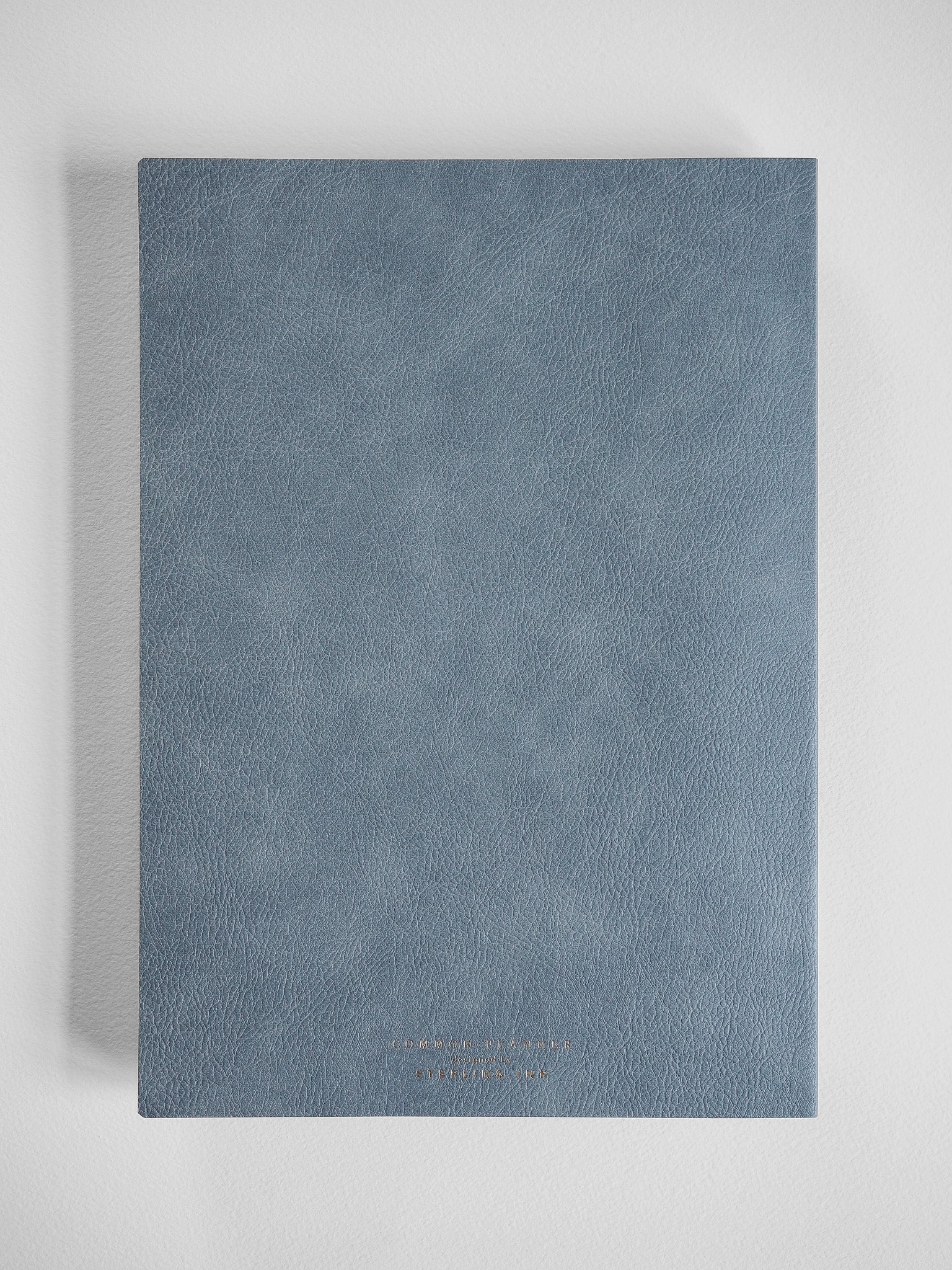 Sleek B5 compact planner featuring a solid slate blue, textured faux leather cover, perfect for organized year-long scheduling.