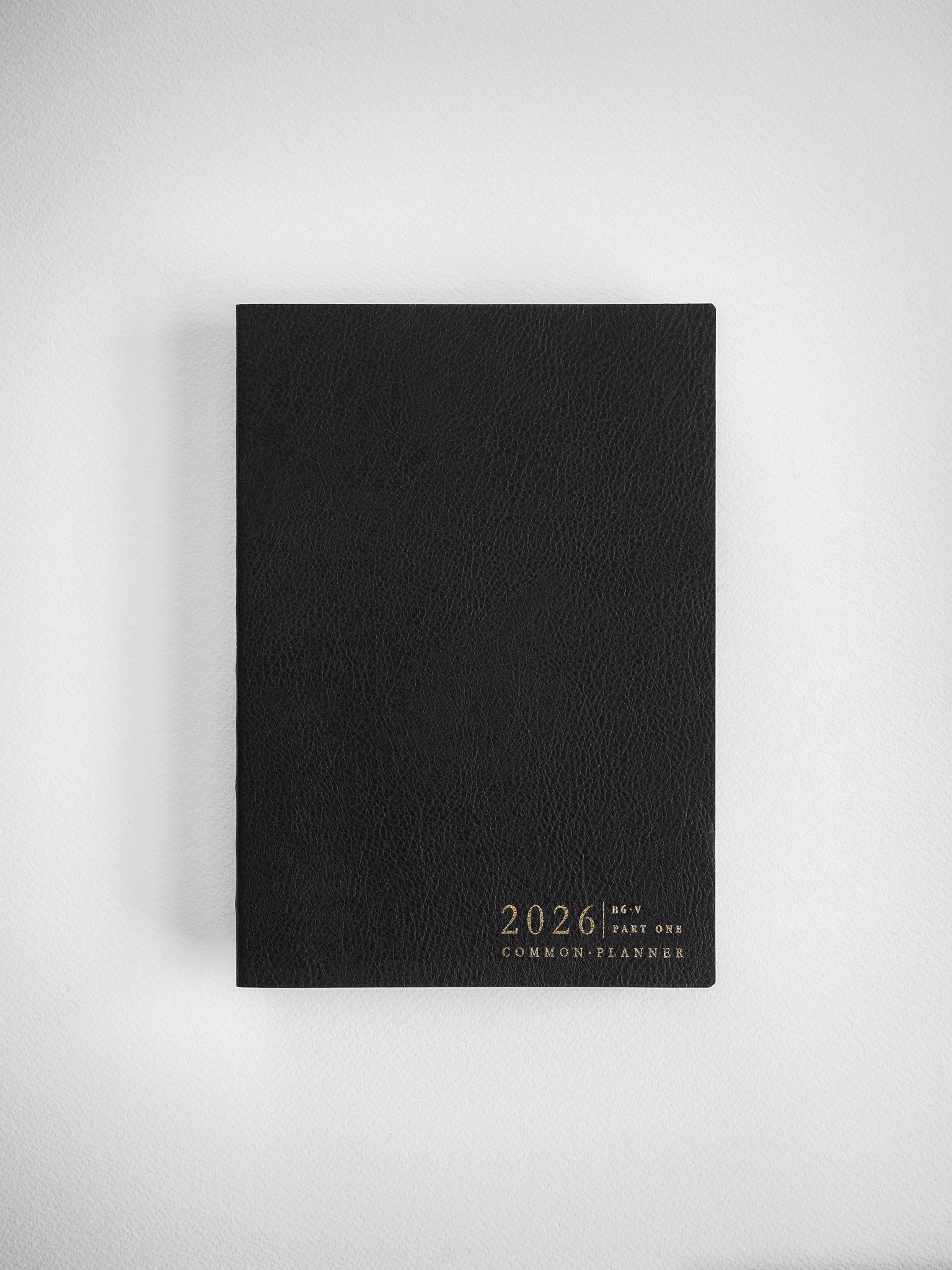 Sleek black B6 vertical planner, embossed with white text reading "2026 Common Planner," designed for minimalist organization and tracking.