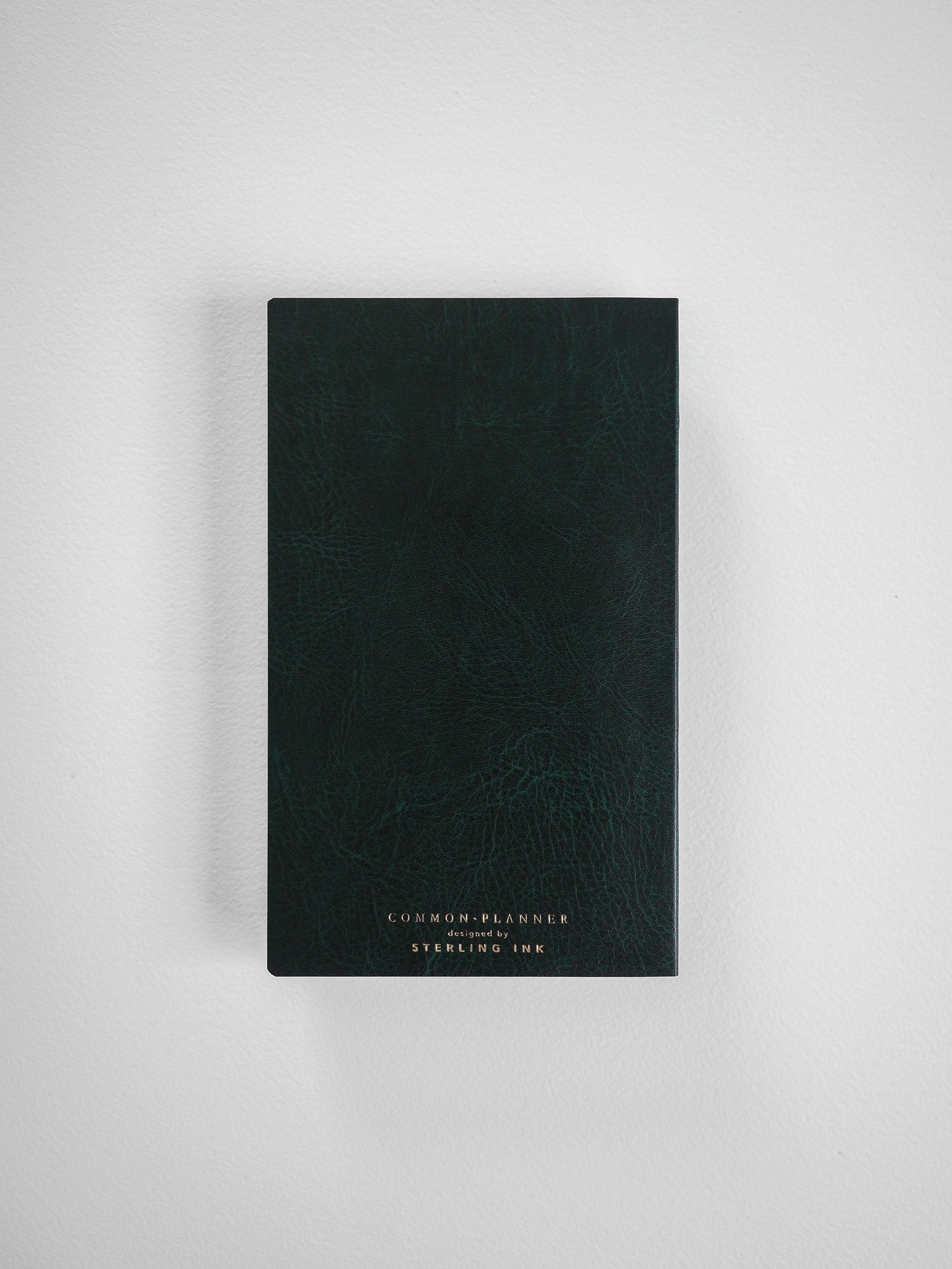 Sleek B6 Common Planner in deep, textured forest green, featuring minimal centered branding from Sterling Ink.