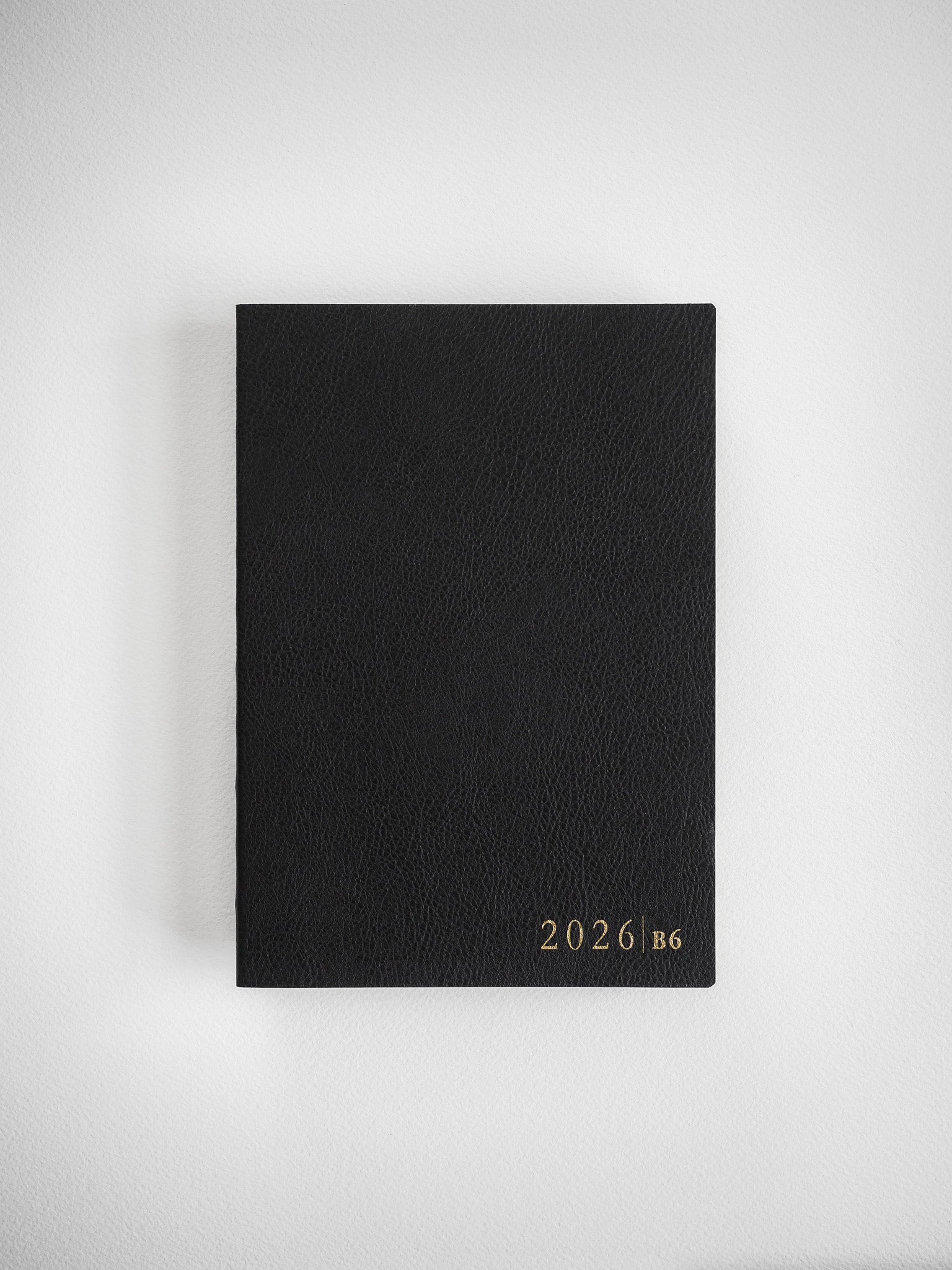 Minimalist B6 vertical core planner featuring a matte black cover with clean, centered white text displaying "2026 B6" for organization.