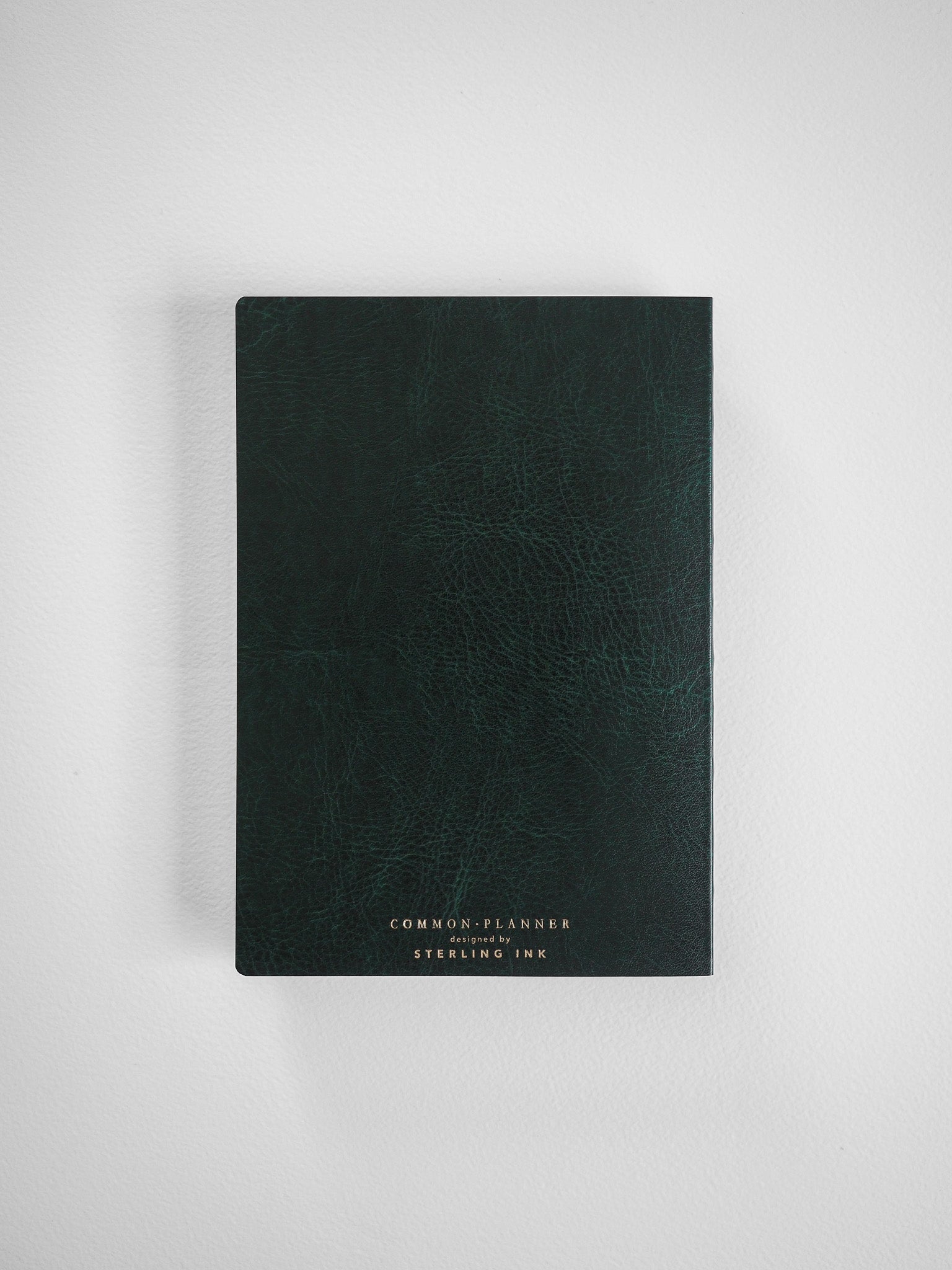 Dark, textured planner cover with a sophisticated matte finish and minimalist white lettering that reads 'COMMON PLANNER' and 'designed by STERLING INK'.