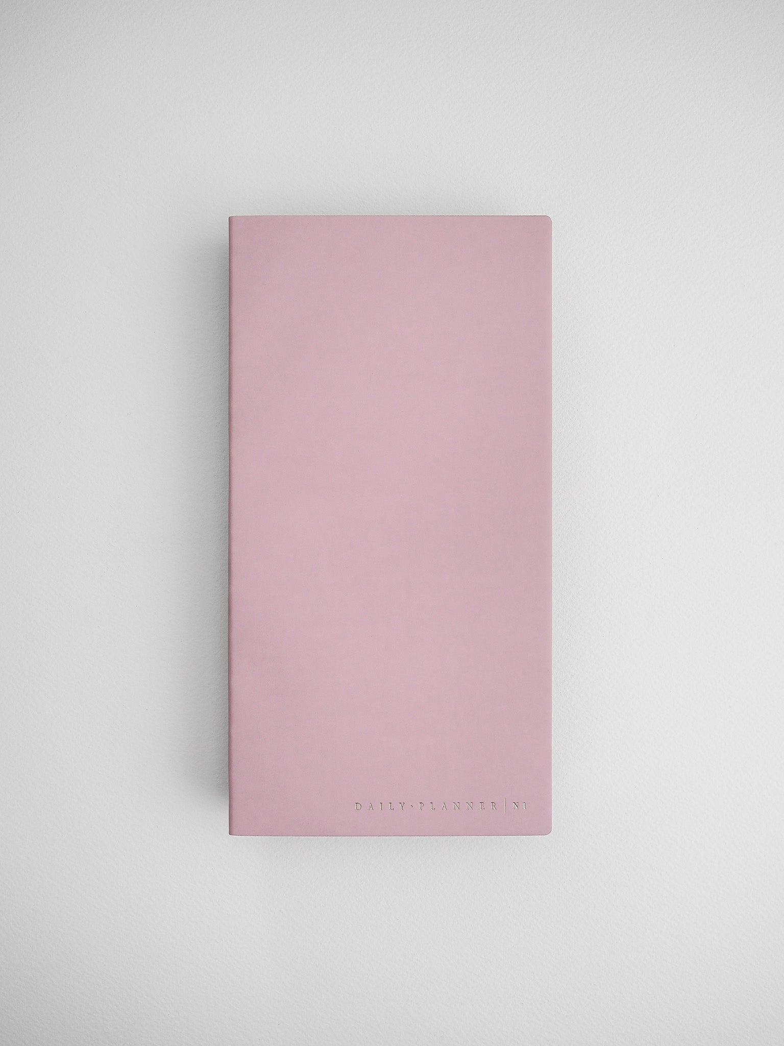 Blush pink undated daily planner notebook with a solid, minimalist cover and "DAILY PLANNER | N1" branding printed near the bottom.