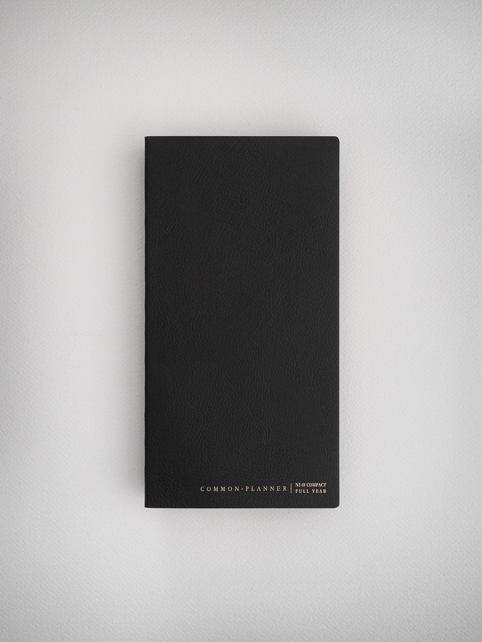 Minimalist black compact planner with a matte, structured cover, featuring "Common Planner" branding and designed for comprehensive full year organization.