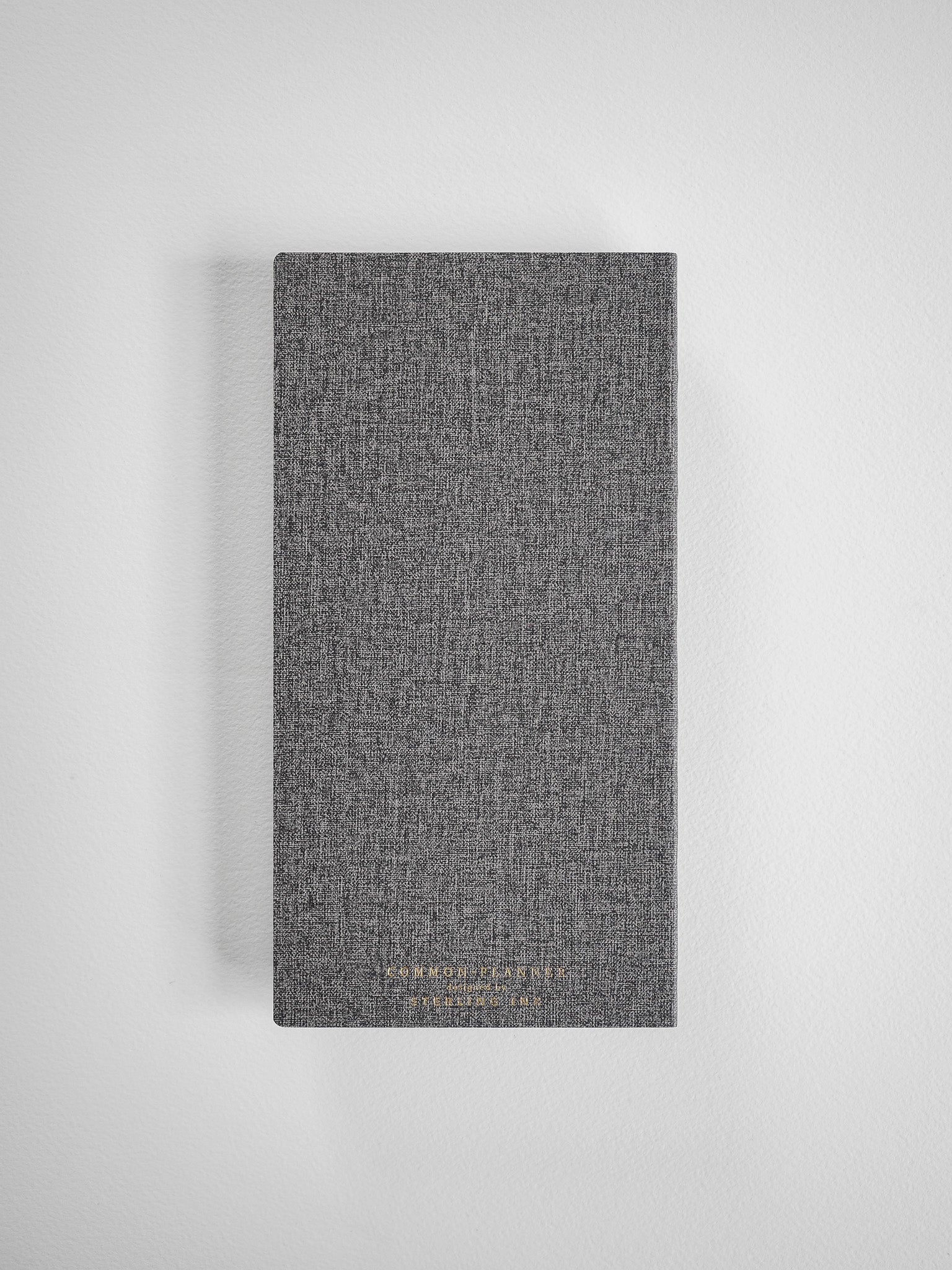 Dark gray textured planner with a woven finish, featuring subtle gold metallic lettering for the 2026 Common Planner.