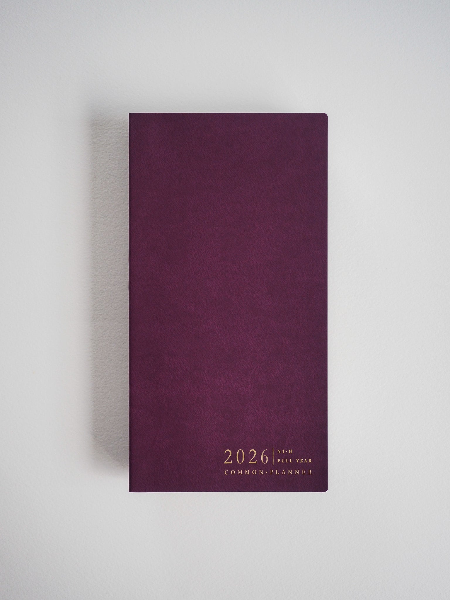 Deep burgundy planner cover featuring minimalist white text announcing "2026 Full Year Common Planner."