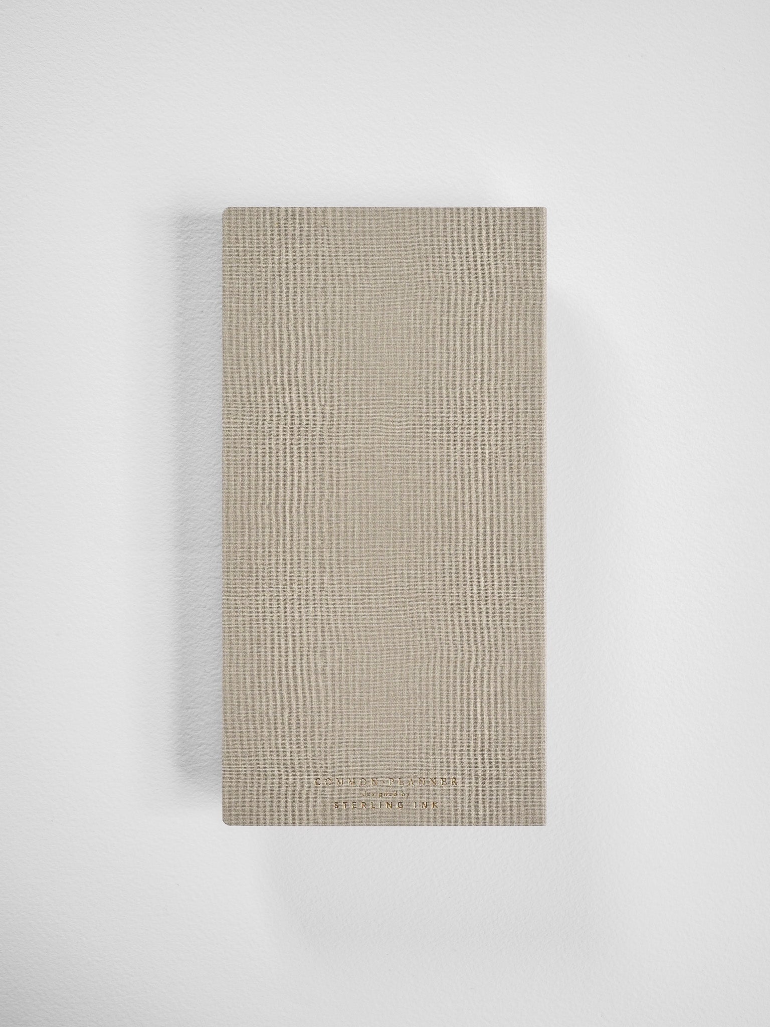 Minimalist beige planner for 2026, featuring a vertical, linen-textured cover and subtle brand lettering from Edmond Planner.