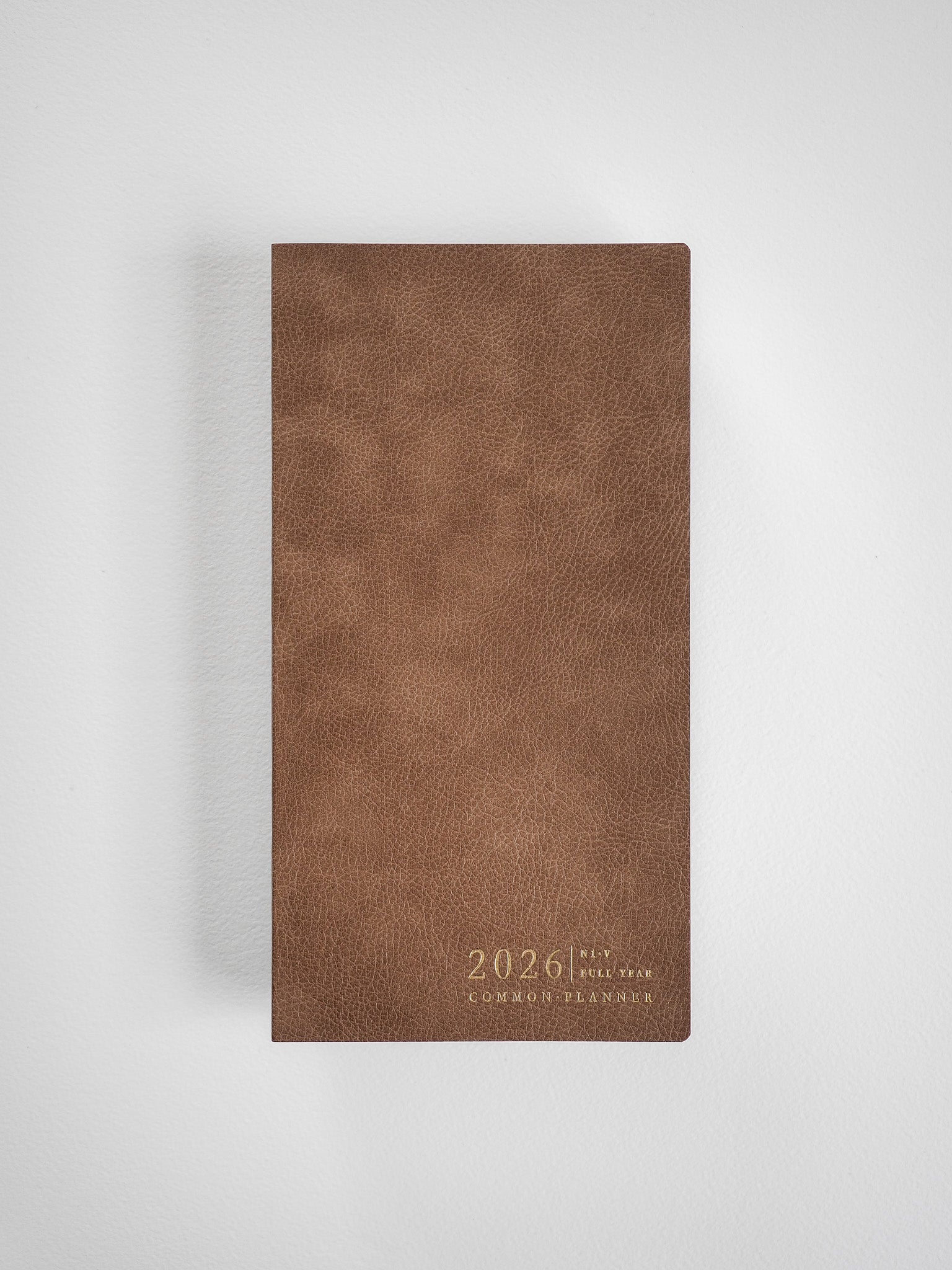 Textured tan faux leather planner cover featuring "2026 Full Year Common Planner" embossed across the vertical front.