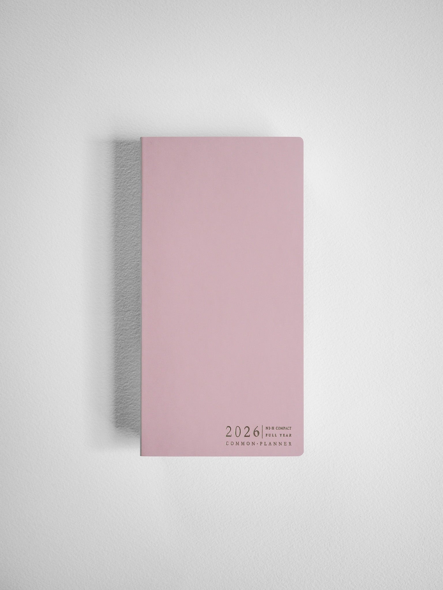 Minimalist blush pink compact planner featuring centered black text that reads "2026 N2-H Compact Full Year Common Planners."