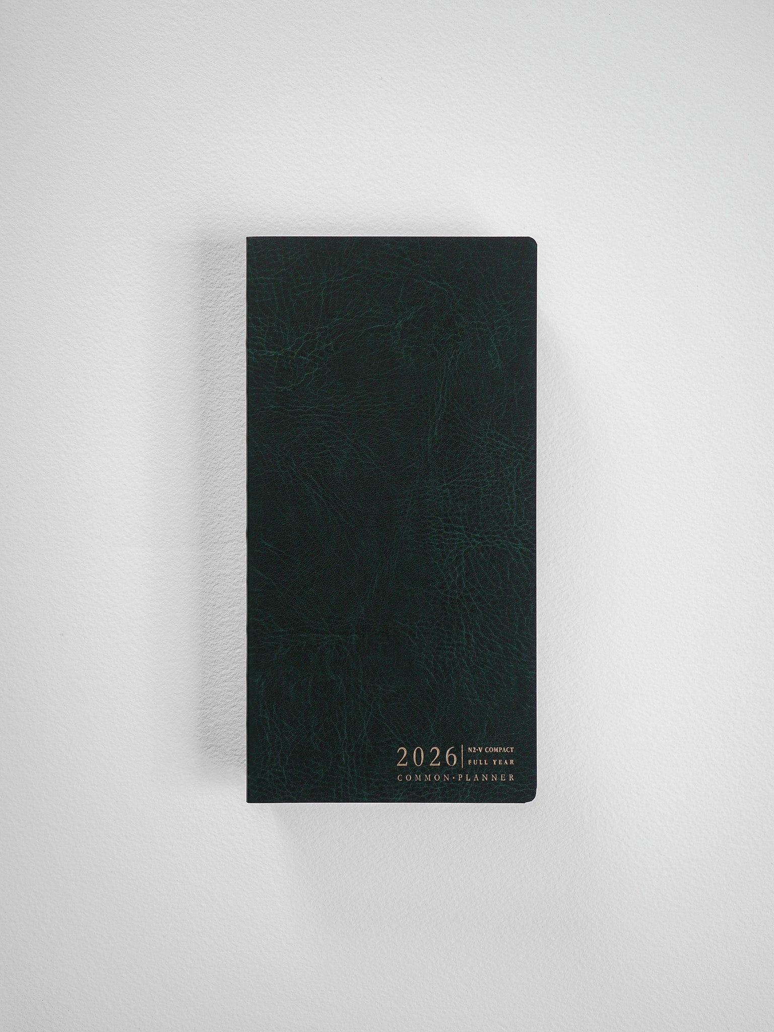 Elegant vertical planner featuring a dark, textured cover printed with the white text "2026 N2 Compact Full Year Common Planner."
