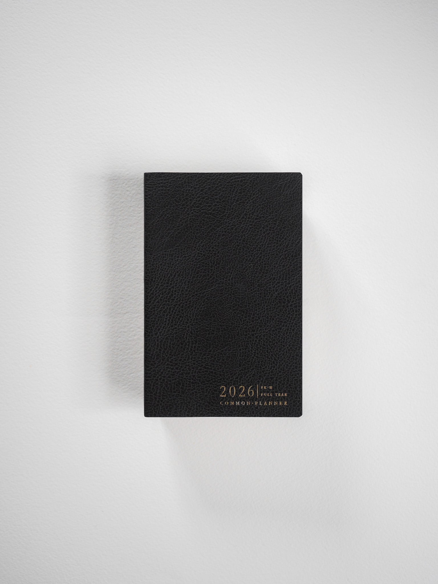 The black horizontal pocket planner features a textured faux leather cover and elegant gold lettering displaying "2026 Common Planner."