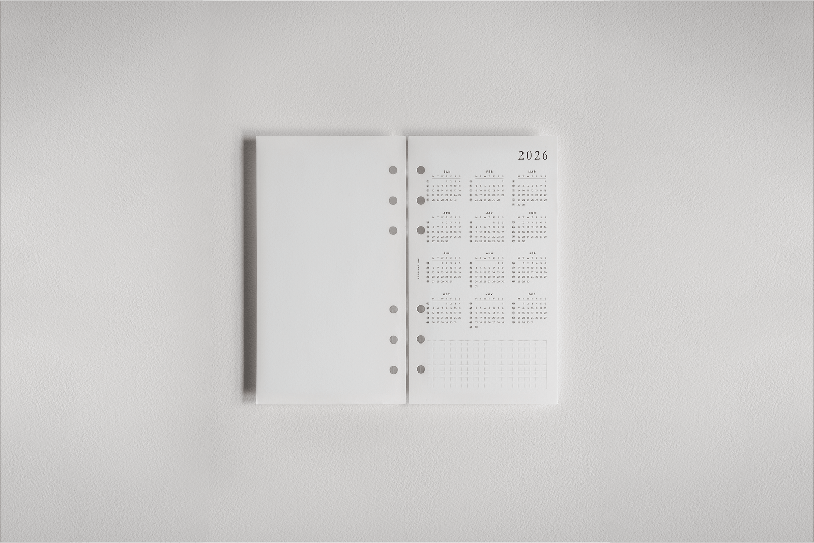Clean white 2026 dated planner inserts featuring organized monthly grids and pre-punched holes for effortless binding into a daily planner.