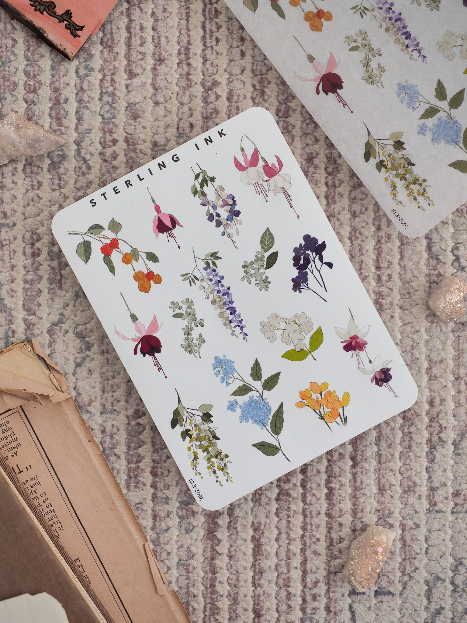 Watercolor sticker sheet featuring diverse botanical elements, including clusters of pink, purple, blue, and yellow spring blossoms arranged on white paper.