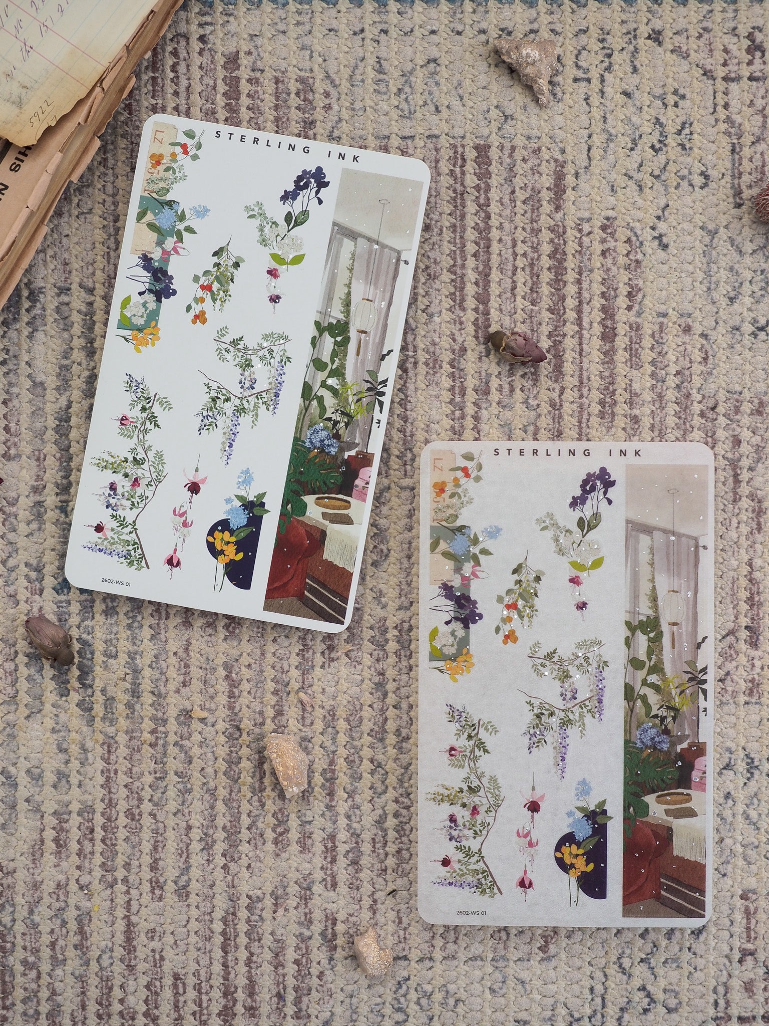Delicate botanical design featuring clusters of deep purple, yellow, and pink wildflowers set against a charming indoor windowsill scene.