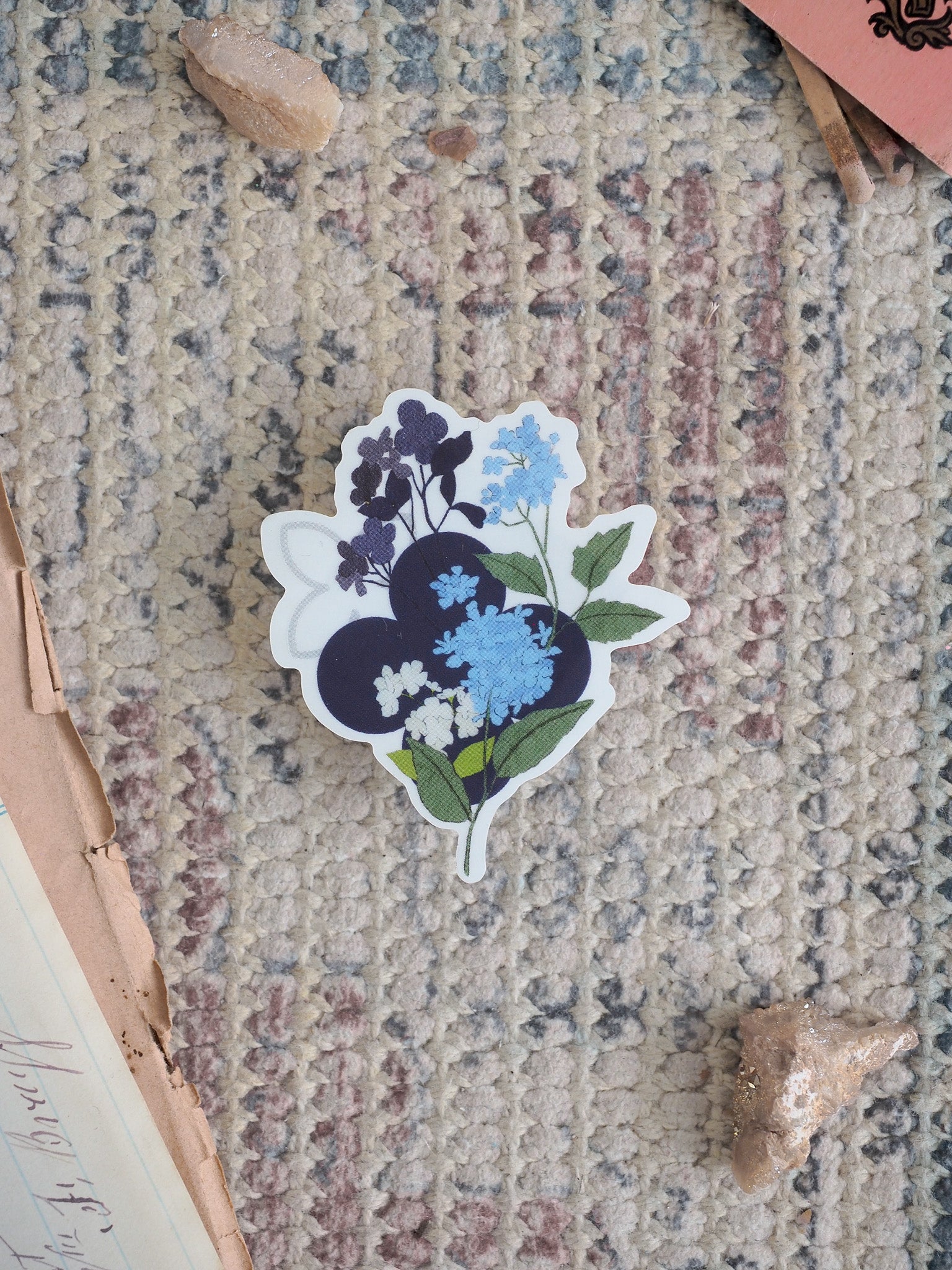 Die-cut sticker featuring a detailed illustration of a blueberry vine, showing deep indigo berries, soft blue blossoms, and rich green leaves.