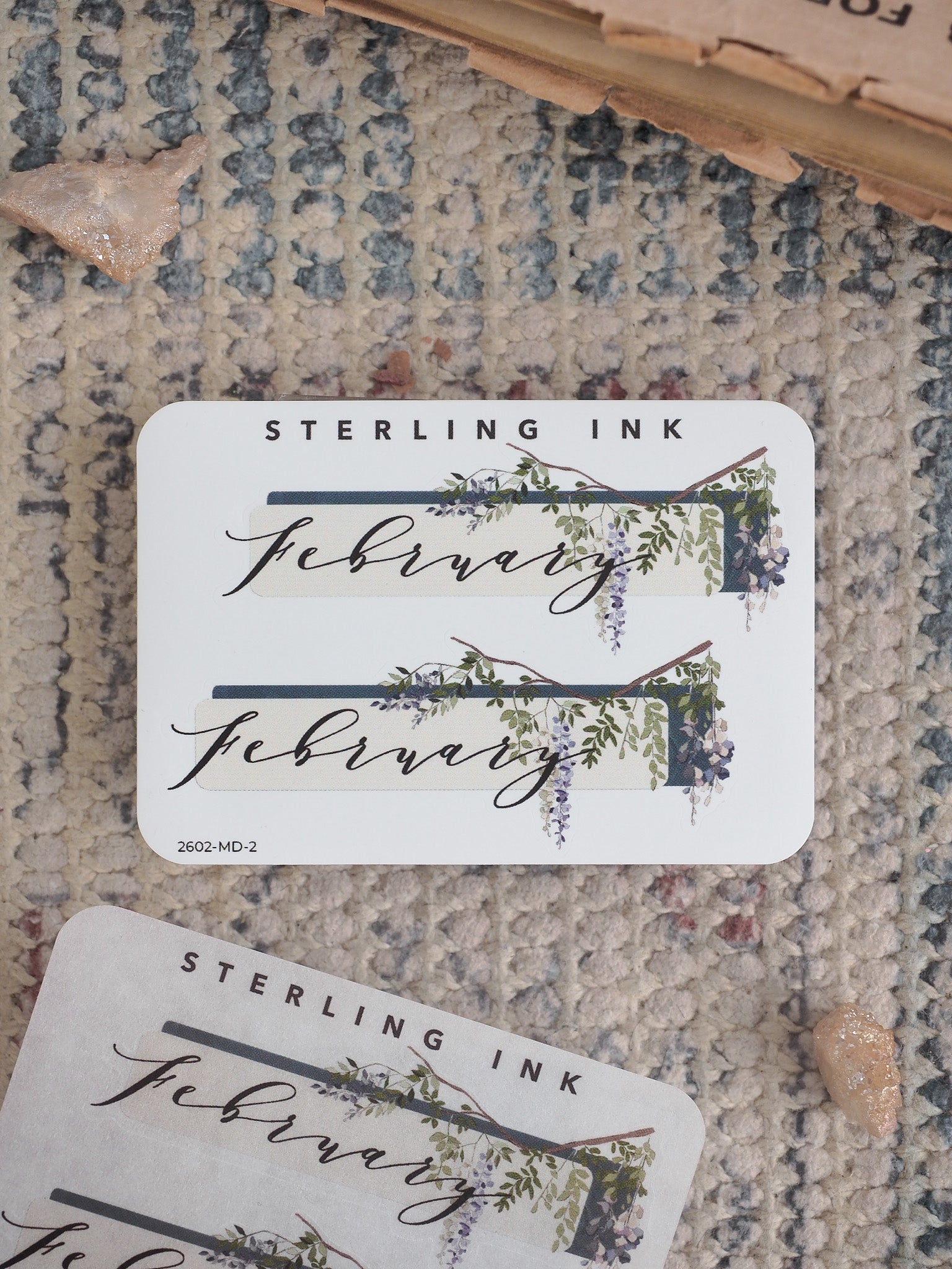 Rustic February planner sticker featuring elegant script and delicate watercolor vines of green foliage and purple blossoms.