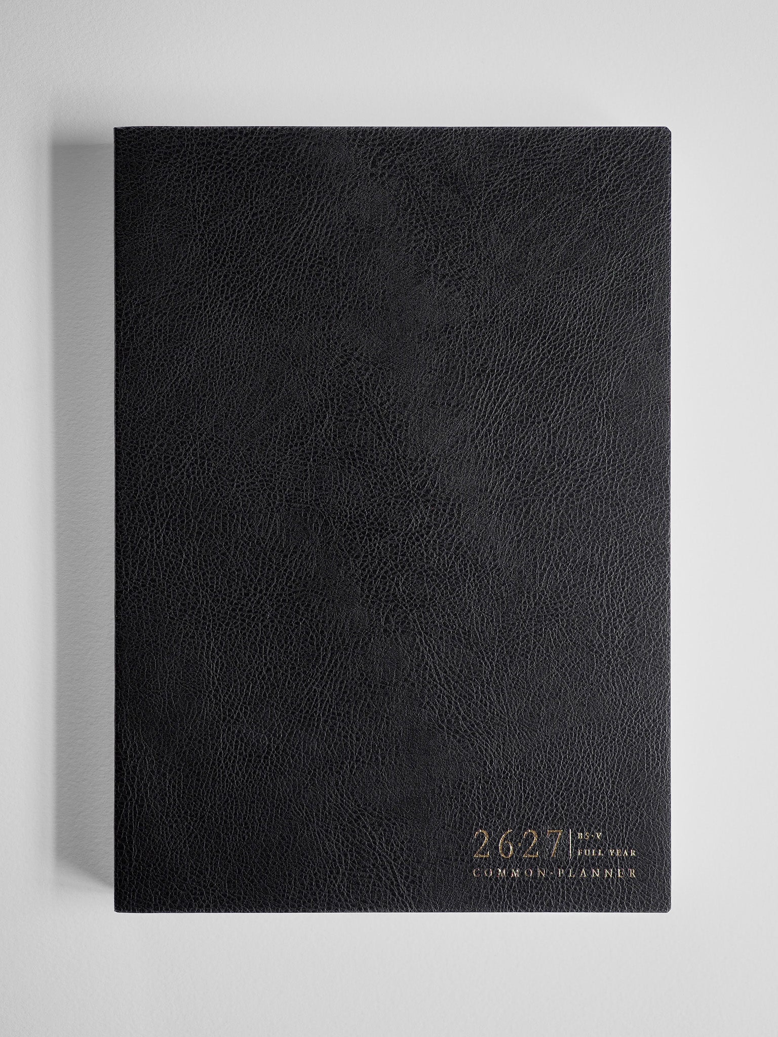 Sleek black academic planner featuring a textured, faux leather cover and elegant gold foil text displaying "2026-2027 Common Planner."