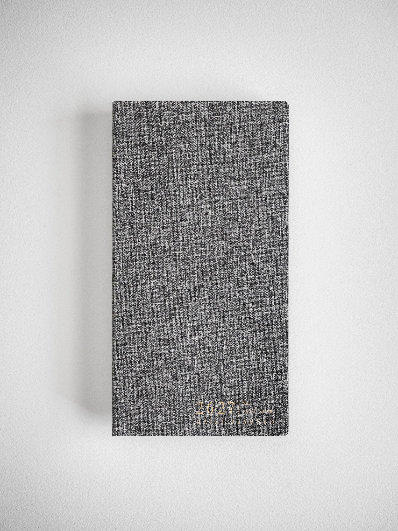 Sophisticated daily planner cover in a textured, dark charcoal gray fabric, subtly marked with academic branding for the 2026–2027 school year.