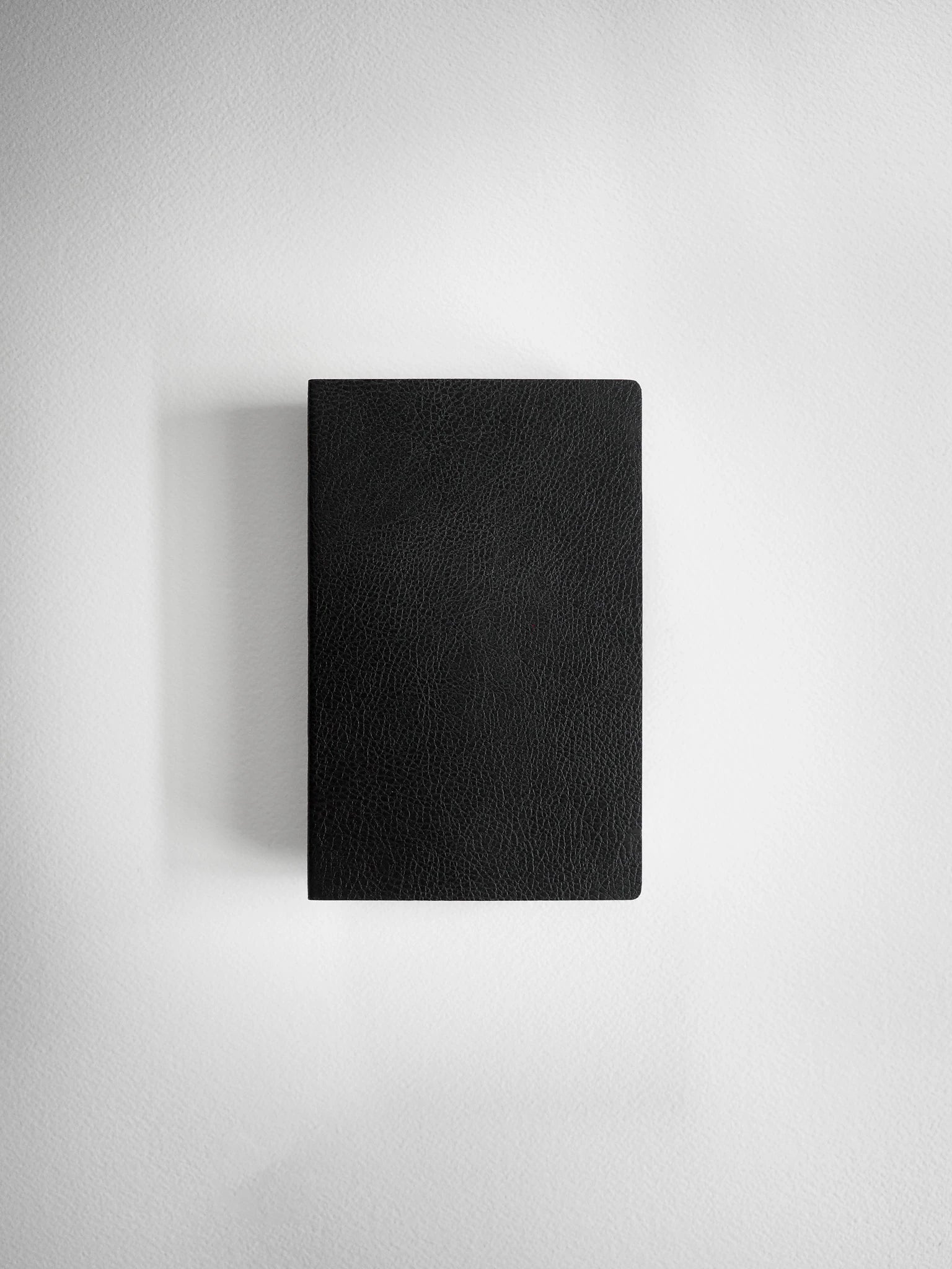 A minimalist black textured leather notebook or journal with a clean rectangular shape, shown from a top-down perspective against a light gray background.
#Color_Onyx
