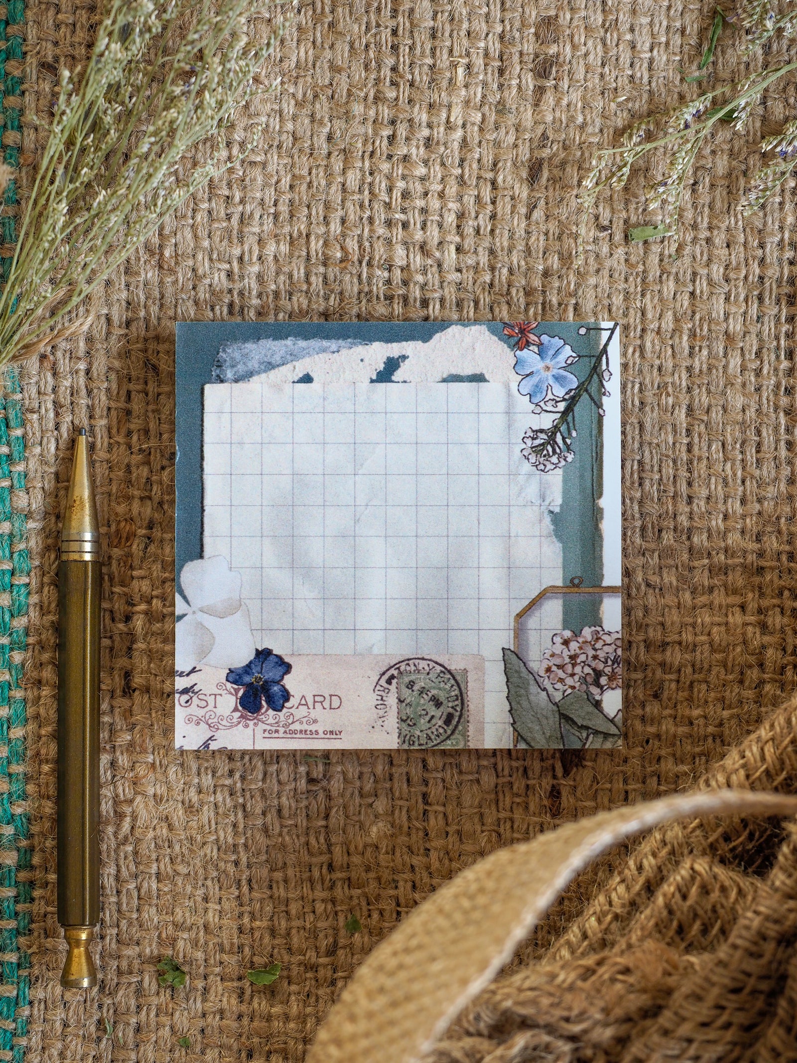 Stationery featuring a gridded design and a beautiful pressed flower border of delicate blue and white blossoms.