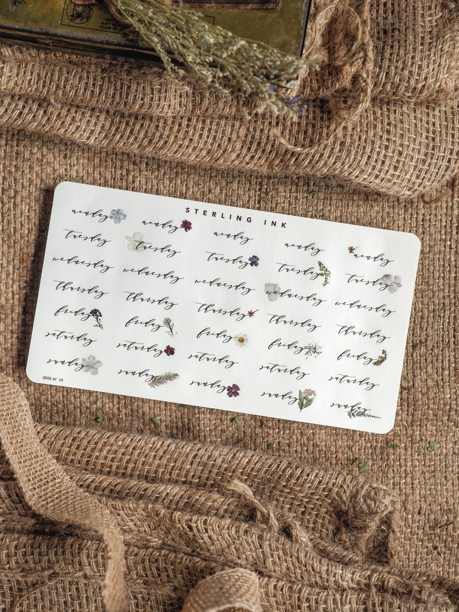 Planner sticker sheet displaying repeating weekday labels and delicate floral accents in blush and burgundy, perfect for organizing a themed journal or bullet journal.