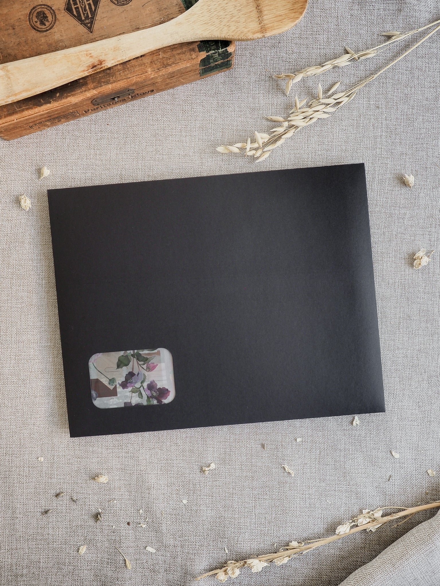 Matte slate-grey card background accented by a delicate rectangular sticker showcasing soft watercolor blooms in muted shades of mauve, pink, and forest green.