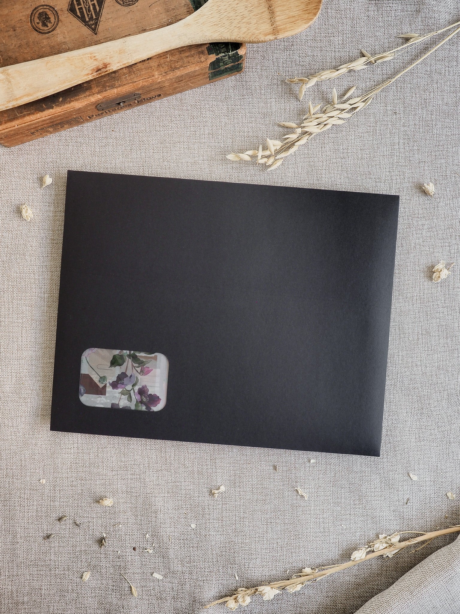 Matte black journal cover featuring a subtle, elegant floral insert of pressed botanicals in shades of deep purple and forest green.