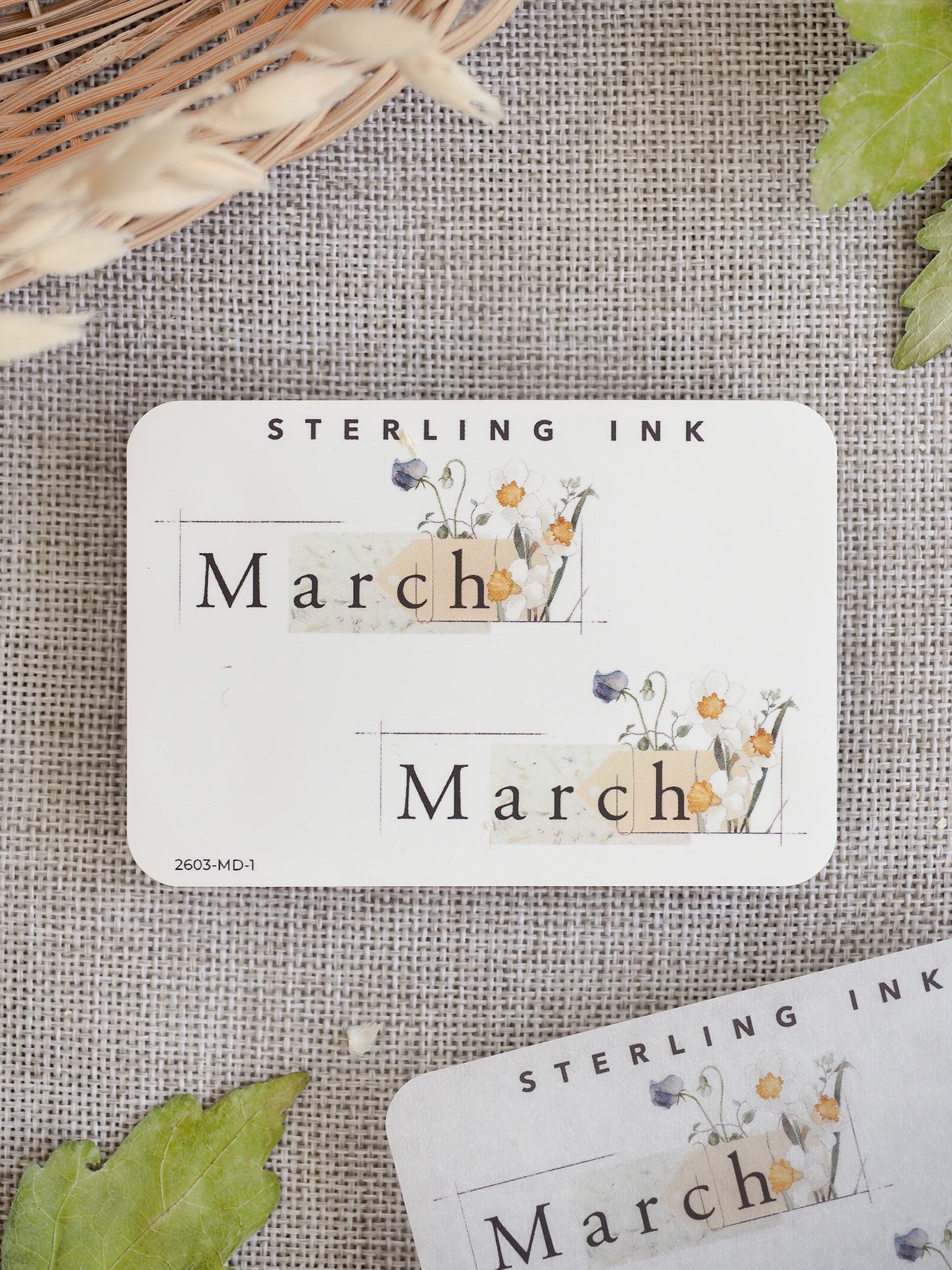 Spring-themed March sticker featuring the word "March" and "STERLING INK" brand text, adorned with a delicate watercolor arrangement of spring wildflowers.