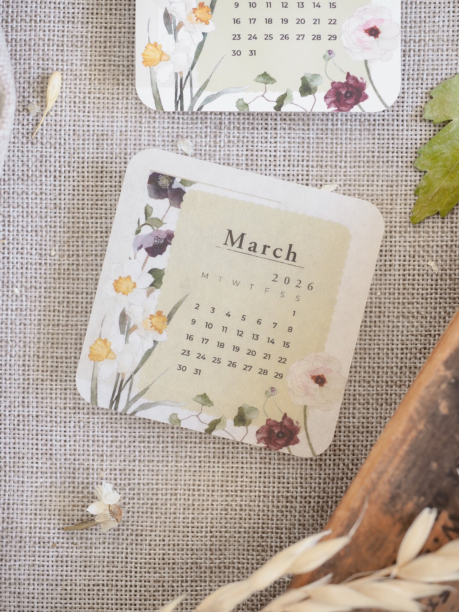 A lovely March 2026 monthly calendar featuring a delicate design of pink and purple watercolor flowers and greenery on a creamy background.