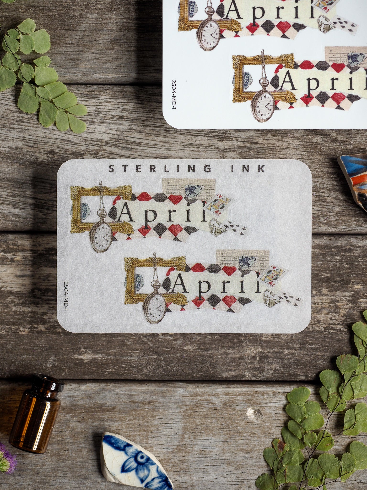 Vintage 'April' month sticker designed with a scrapbook aesthetic, featuring elegant gold ink accents, decorative frames, and ornate pocket watch motifs.