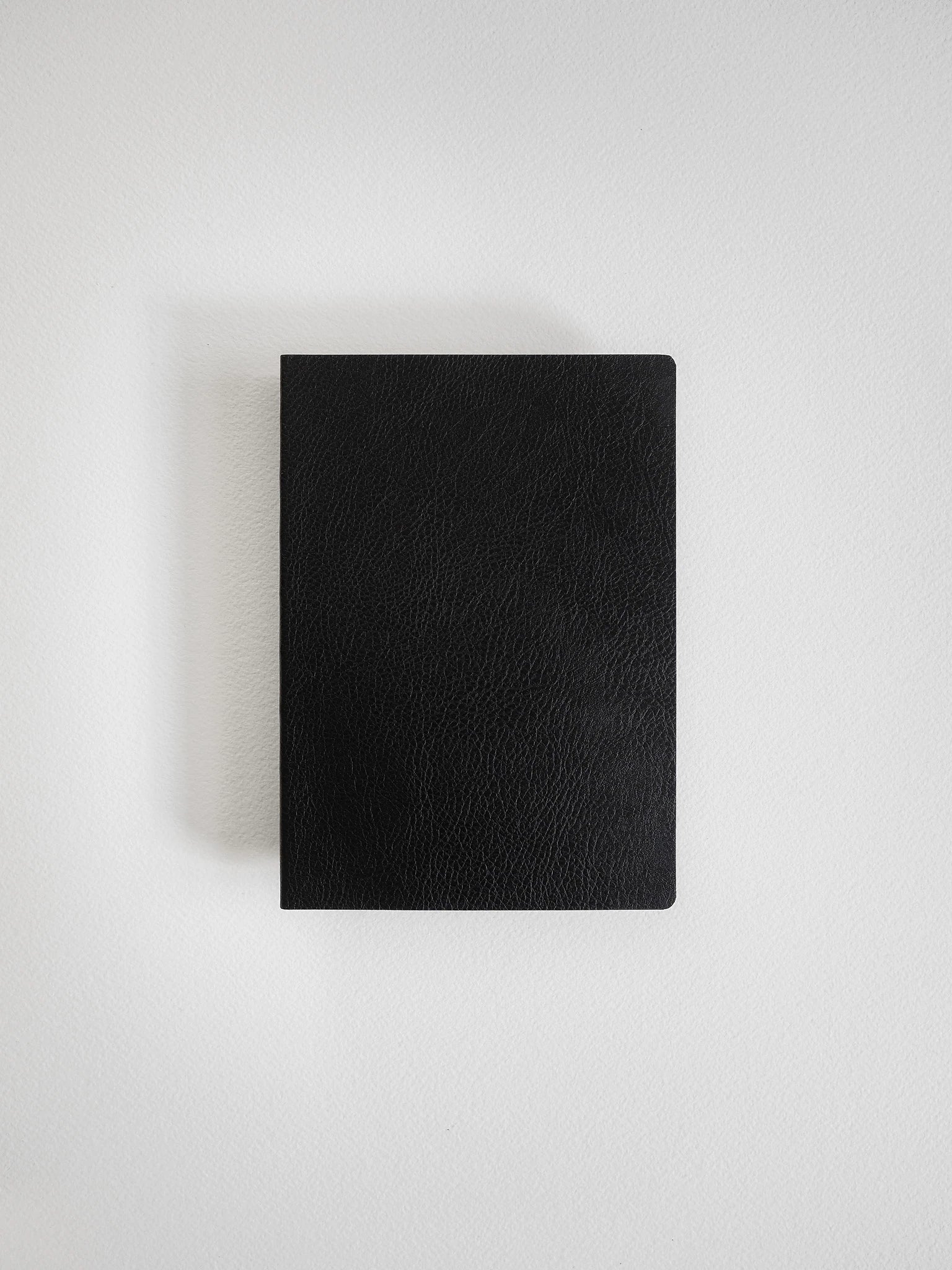 A black textured leather notebook or journal with a rounded bottom corner, shown flat against a light gray background.
#Color_Onyx