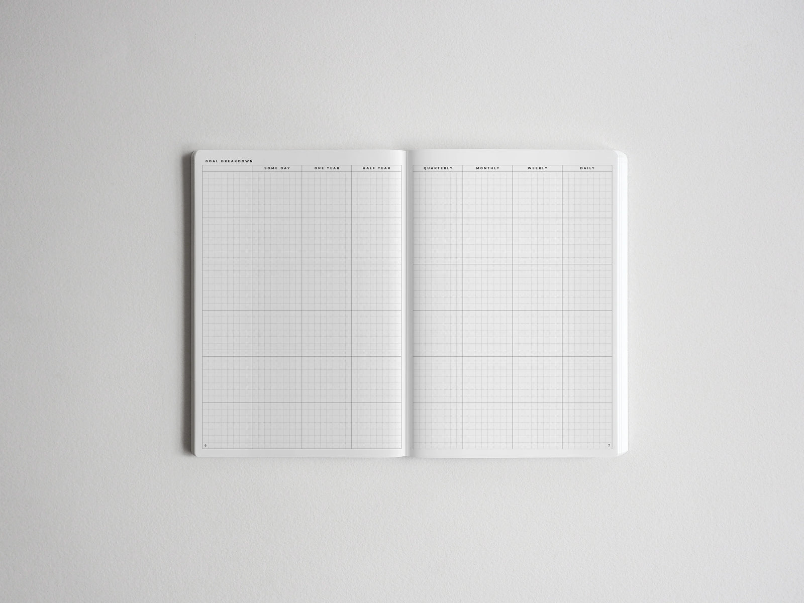 Open planner spread detailing goal breakdown, with structured grids for yearly, quarterly, monthly, weekly, and daily planning and tracking.