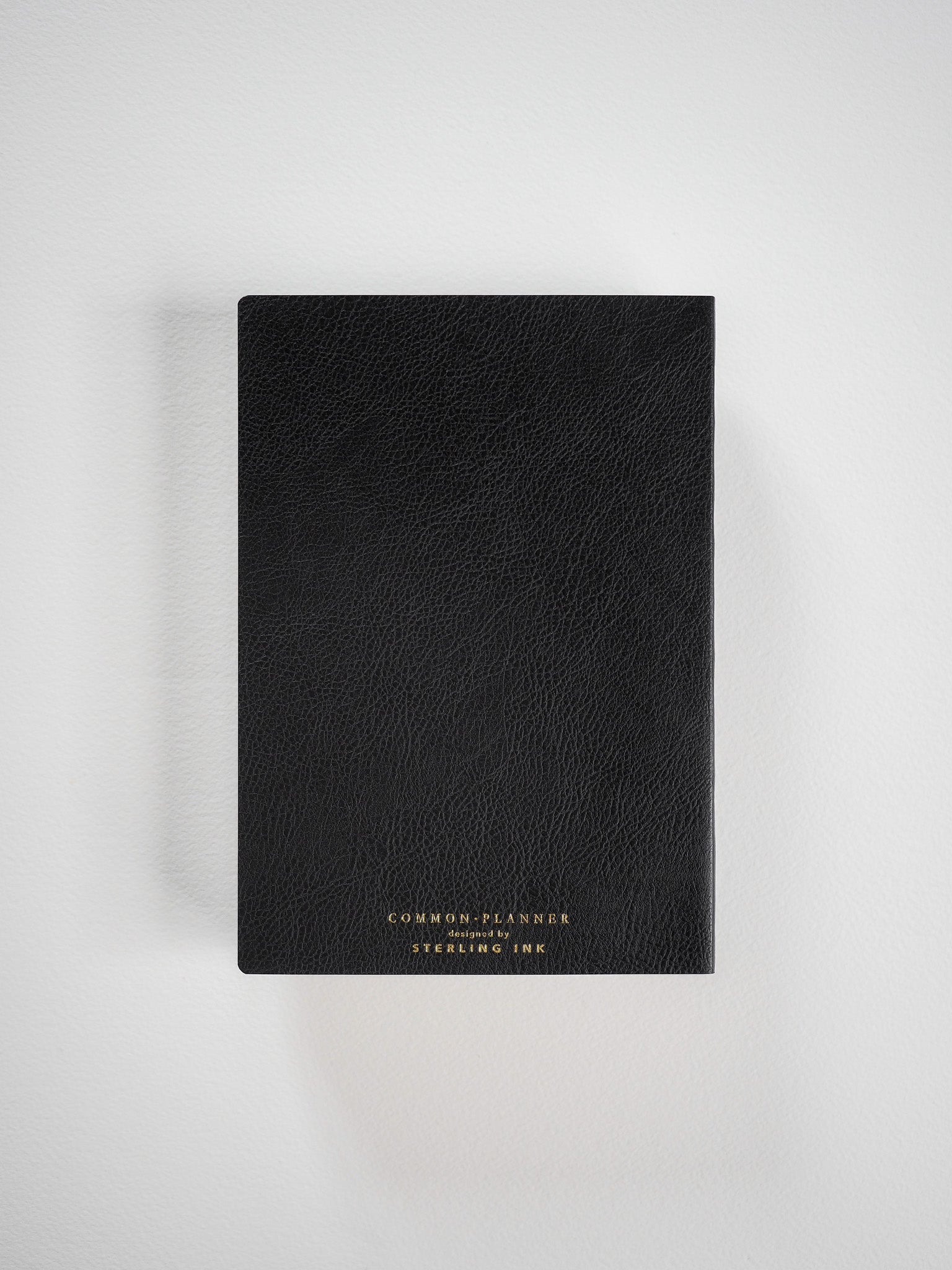 A sophisticated black academic planner with a textured cover, featuring subtle gold-toned foil branding for "Common Planner."