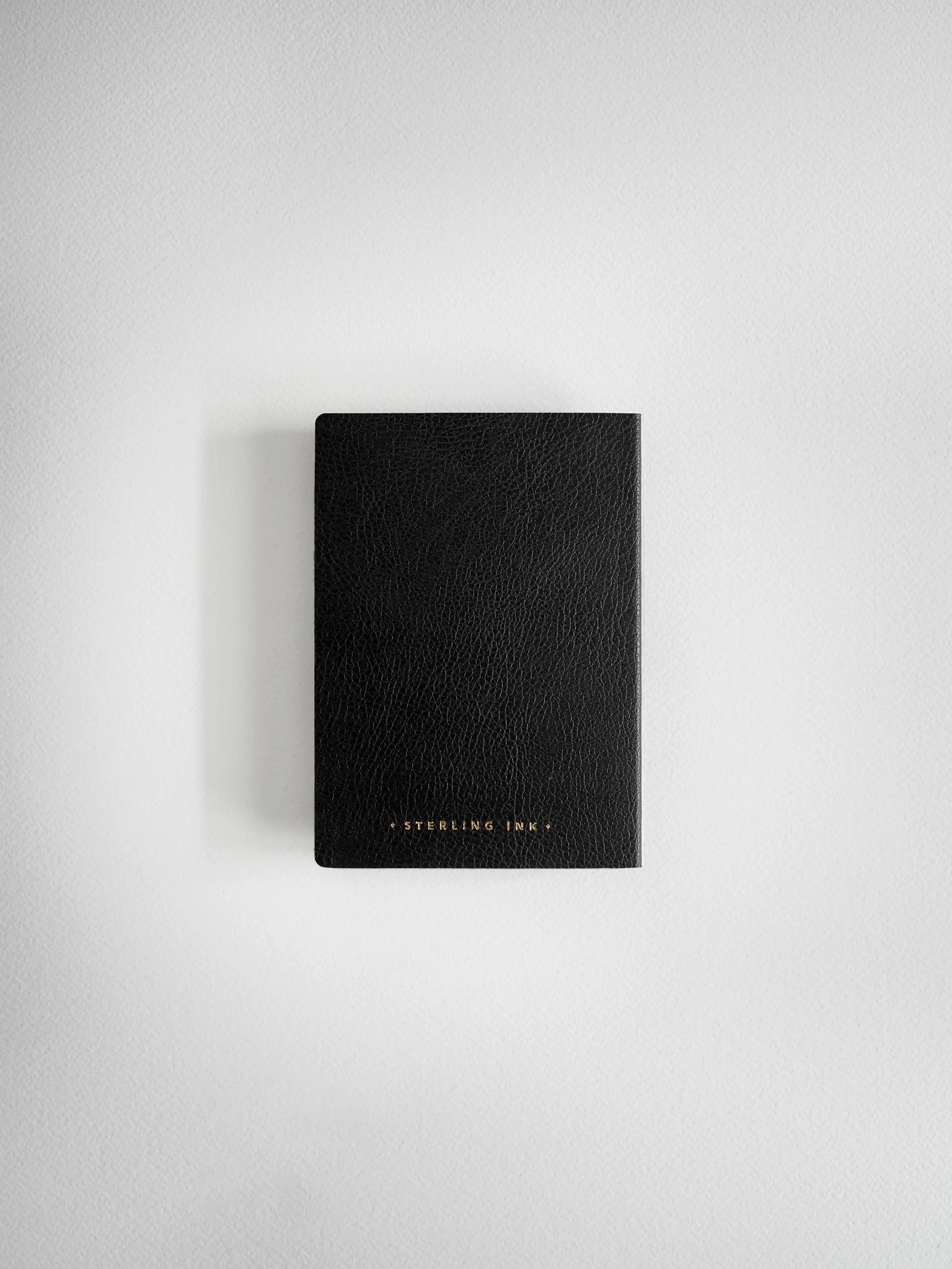 A black textured leather notebook or journal with gold foil lettering that reads 'STERLING LAW' at the bottom, centered on a light gray background.
#Color_Onyx