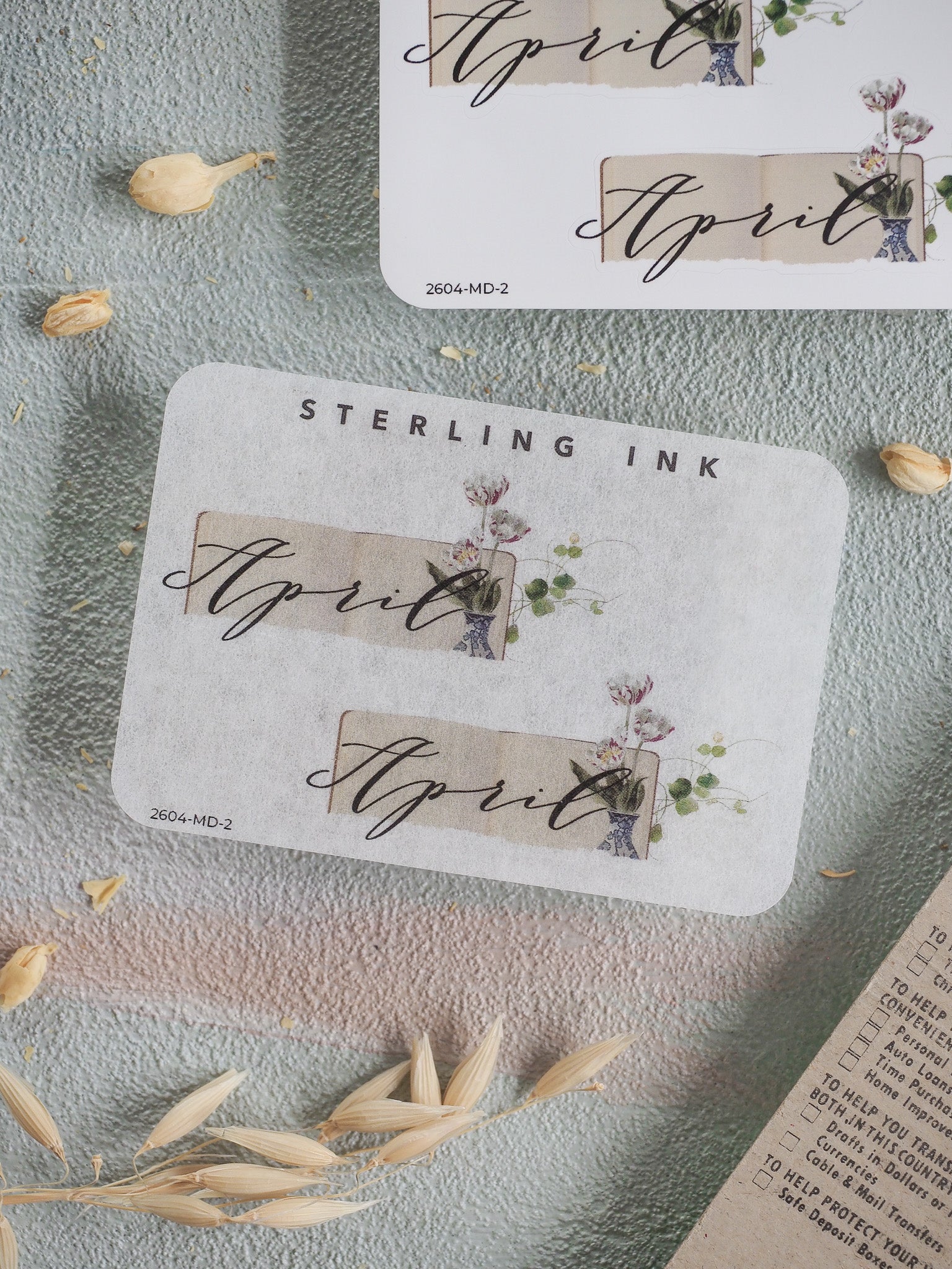 Elegant April month sticker set featuring the name in gold script, set against a cream background with delicate botanical illustrations of blush pink flowers and soft greenery.