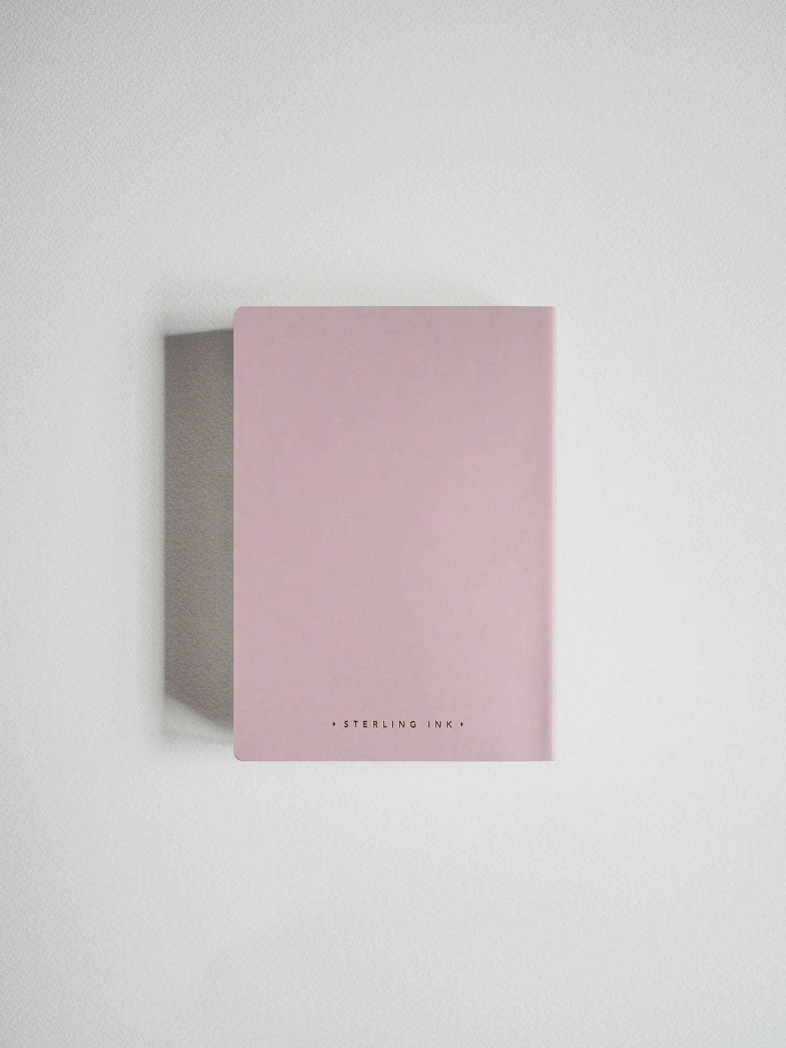 A minimalist pink notebook with a matte finish and a small black text logo at the bottom, displayed on a clean white background with a soft shadow.
#Color_Fairyfloss