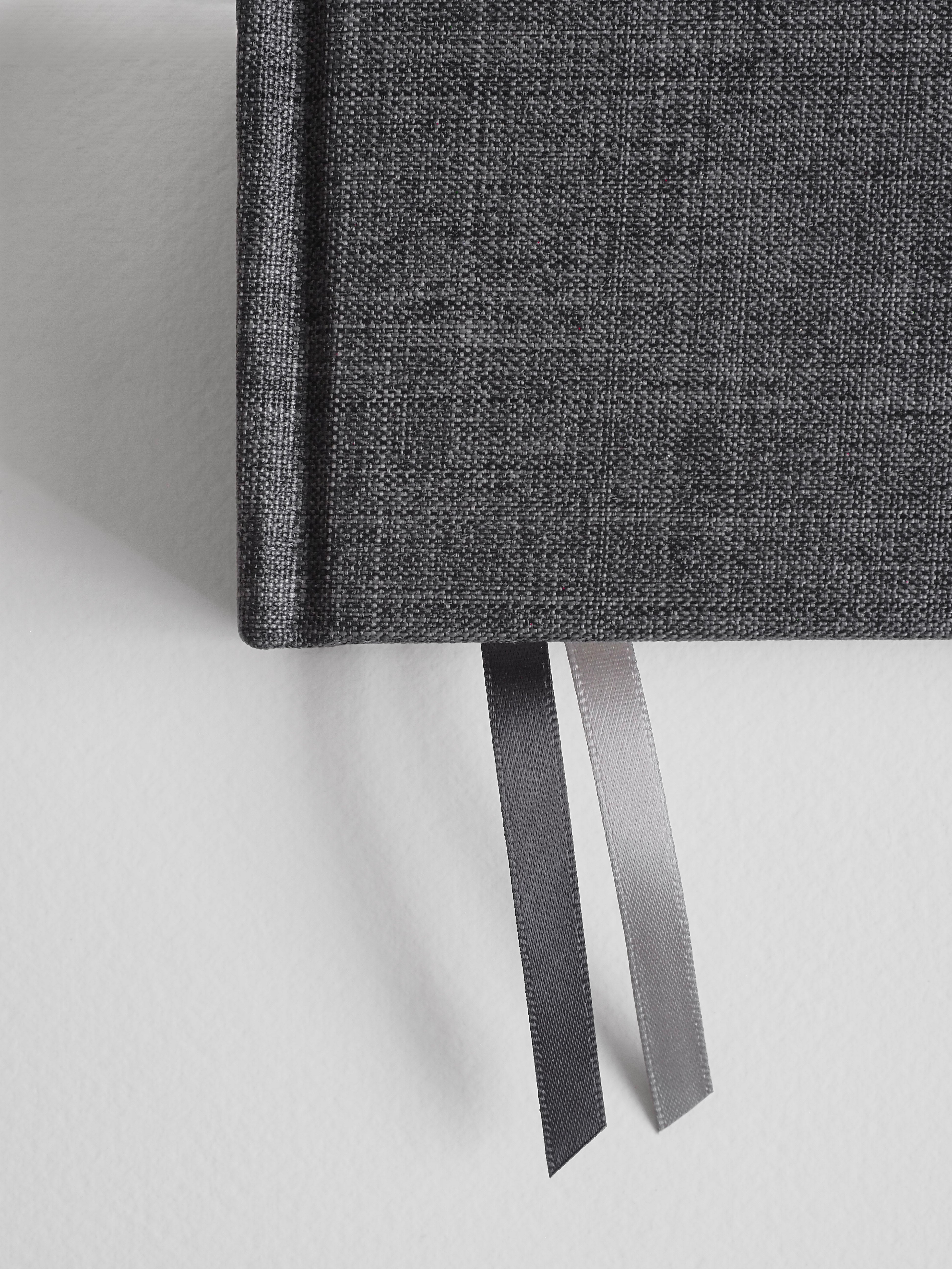Durable B6 academic planner featuring a dark charcoal gray textured fabric cover, complemented by two contrasting satin ribbon bookmarks for comprehensive year organization.