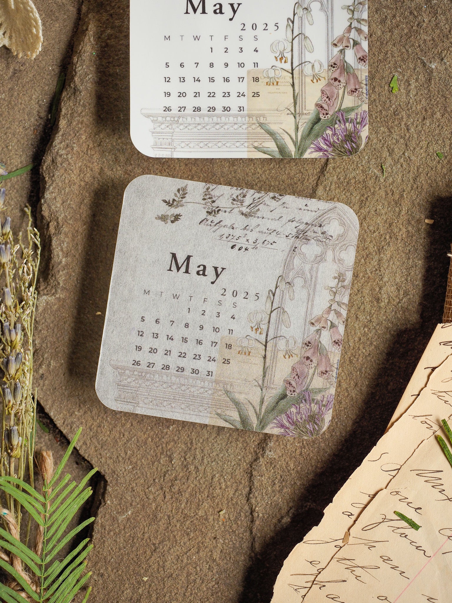 A charming, vintage-style May 2025 monthly calendar featuring a soft botanical border of purple and dusty green florals.