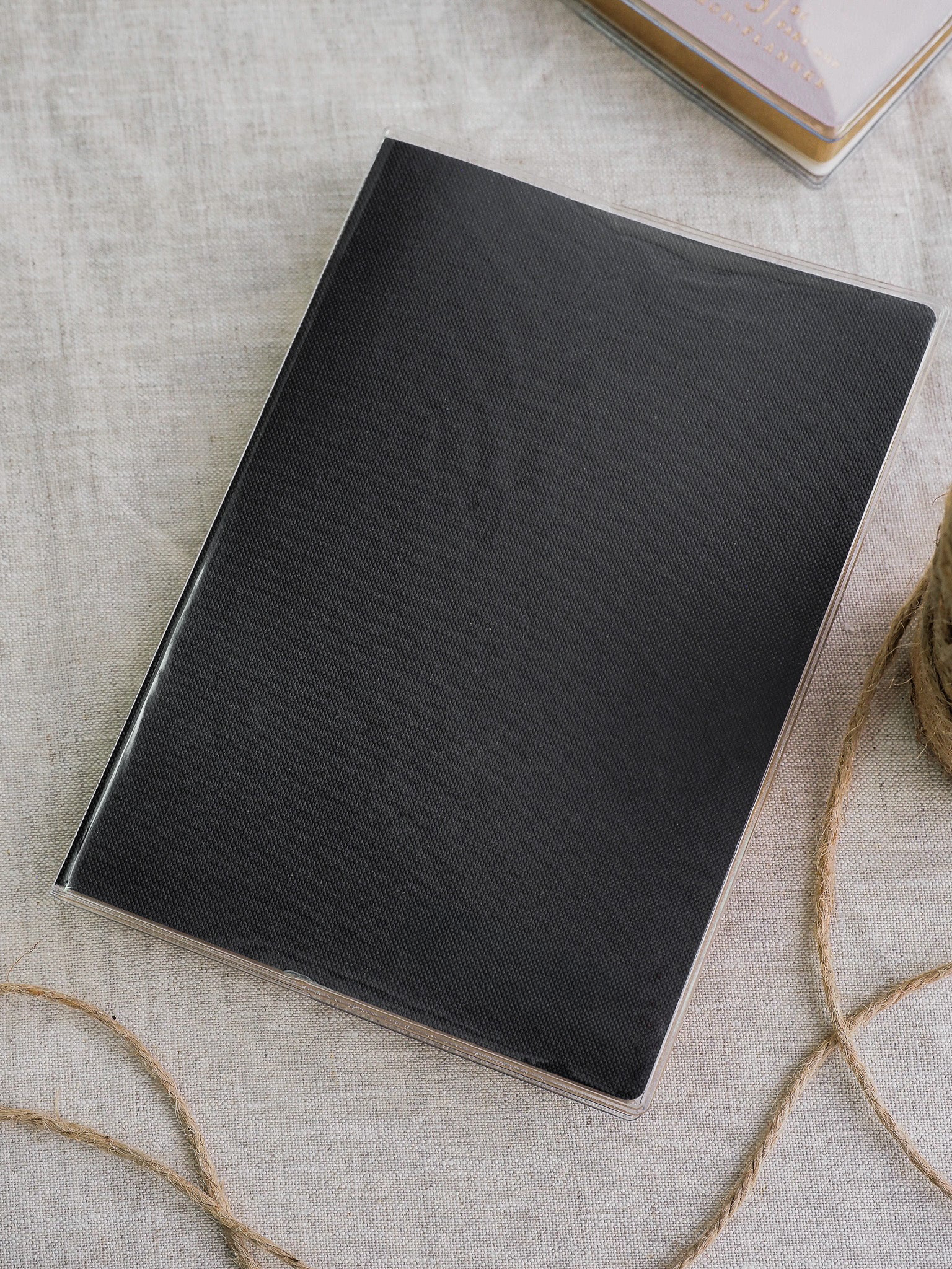 Elegant, solid black rectangular cover with a smooth matte finish, displayed within a clear protective sleeve.